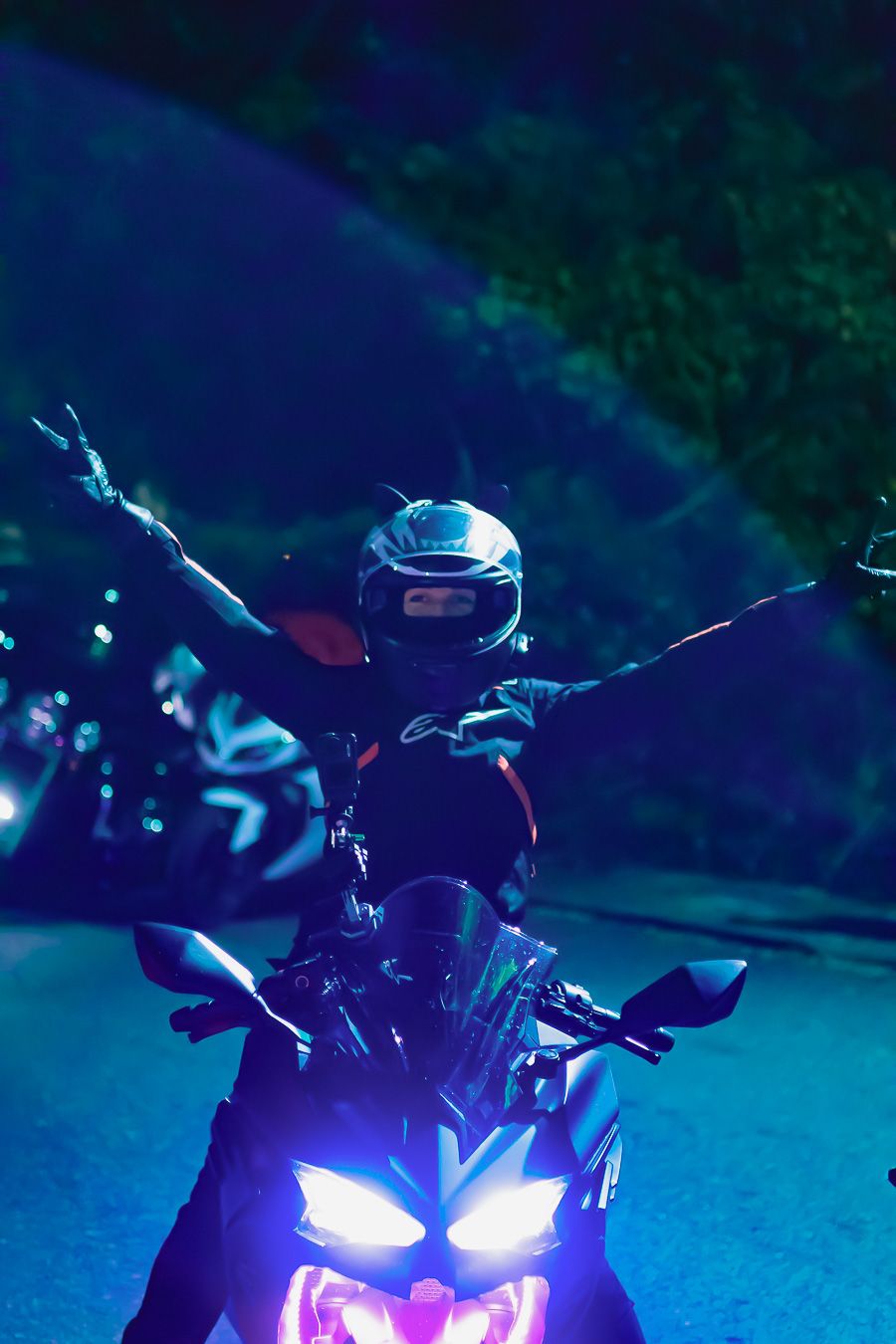 Sport motorcycle headlights glowing in dark blue nighttime setting.