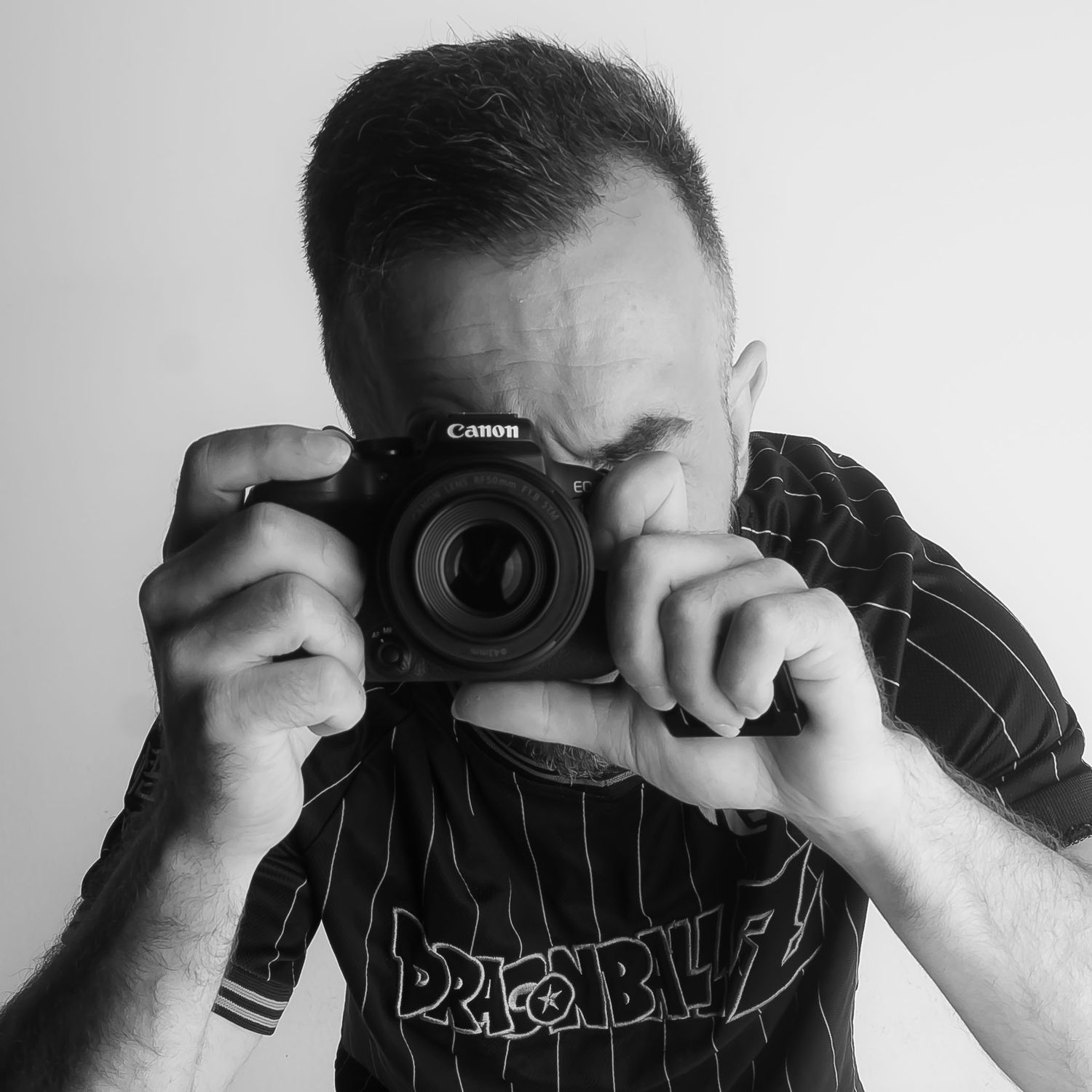 Photographer in black striped shirt taking picture with Canon camera in black and white portrait style.