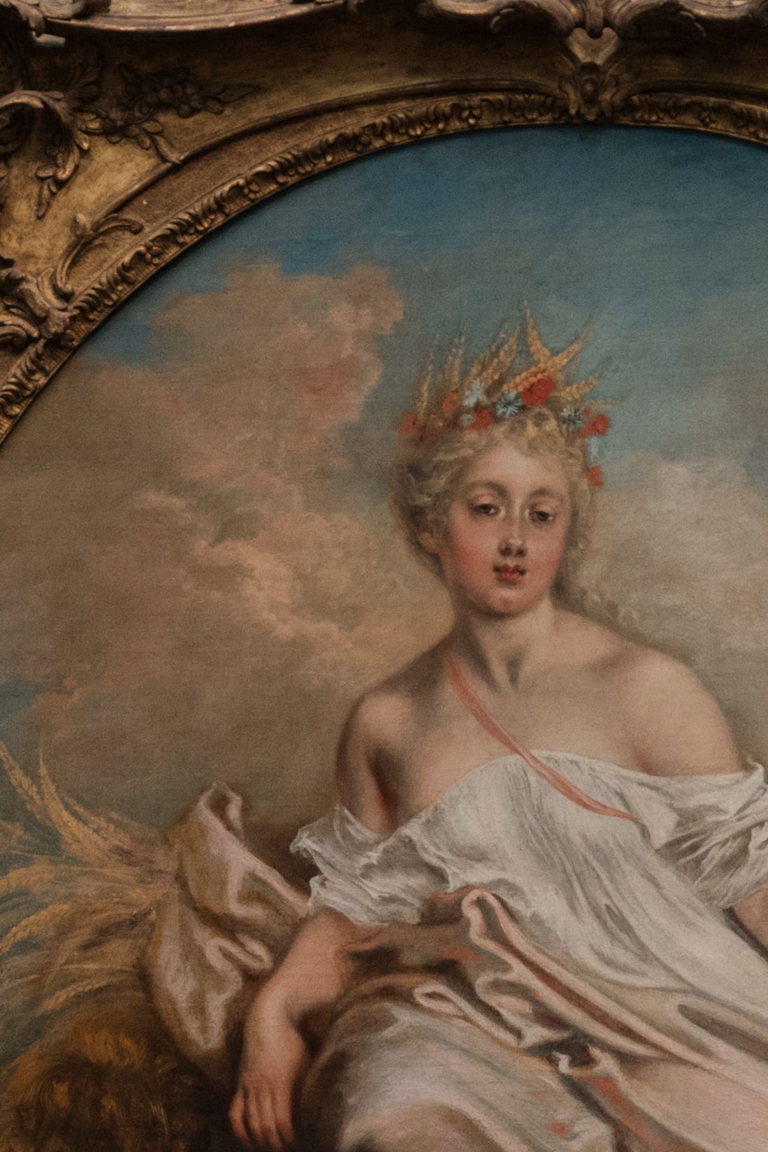 Detail of an ornate classical oil painting depicting a crowned woman in flowing white robes.