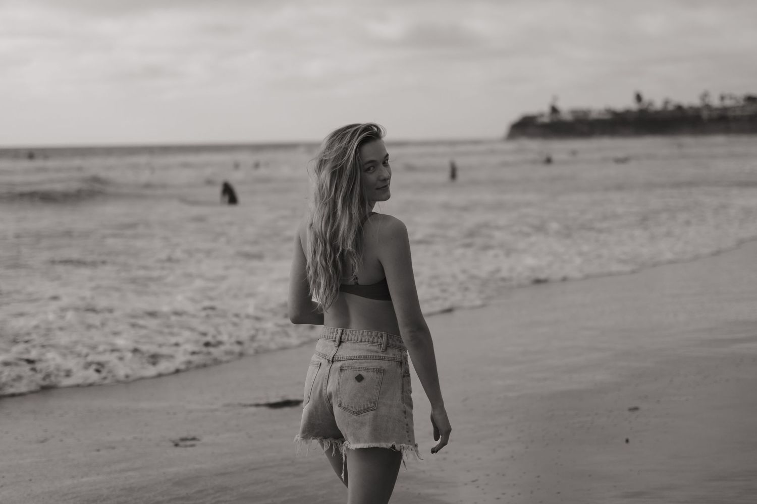 Young woman with long blonde hair walking along Pacific Beach in San Diego, California.