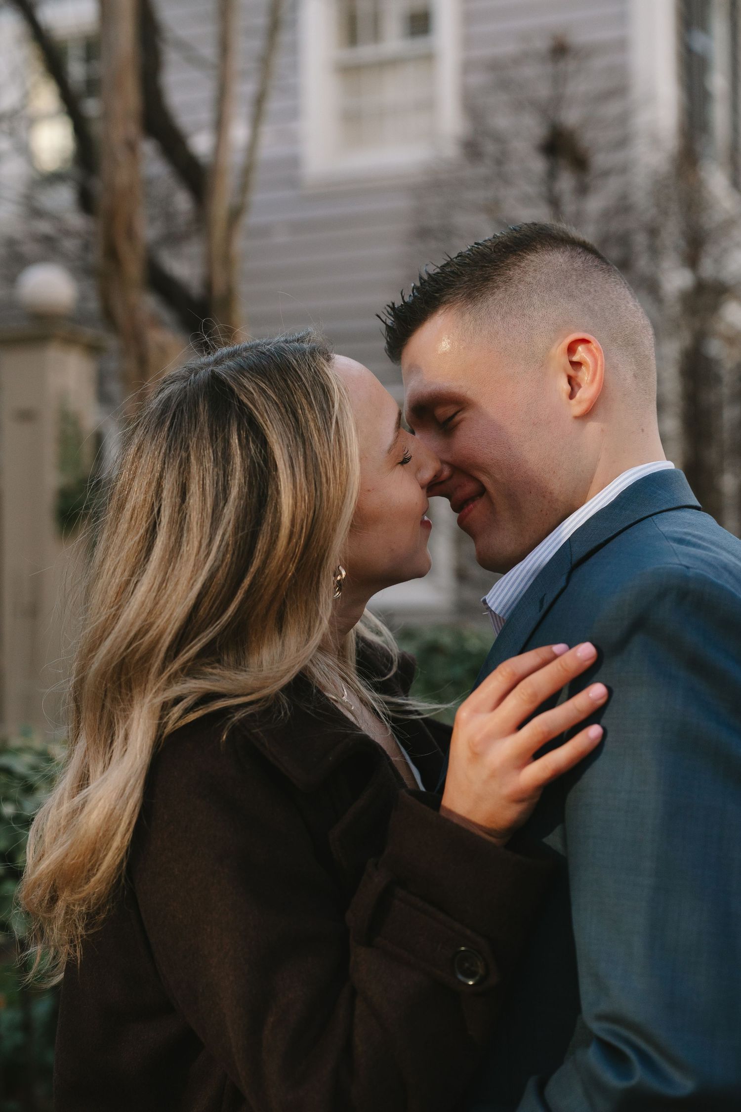 Couple sharing a romantic kiss outdoors during their engagement session.