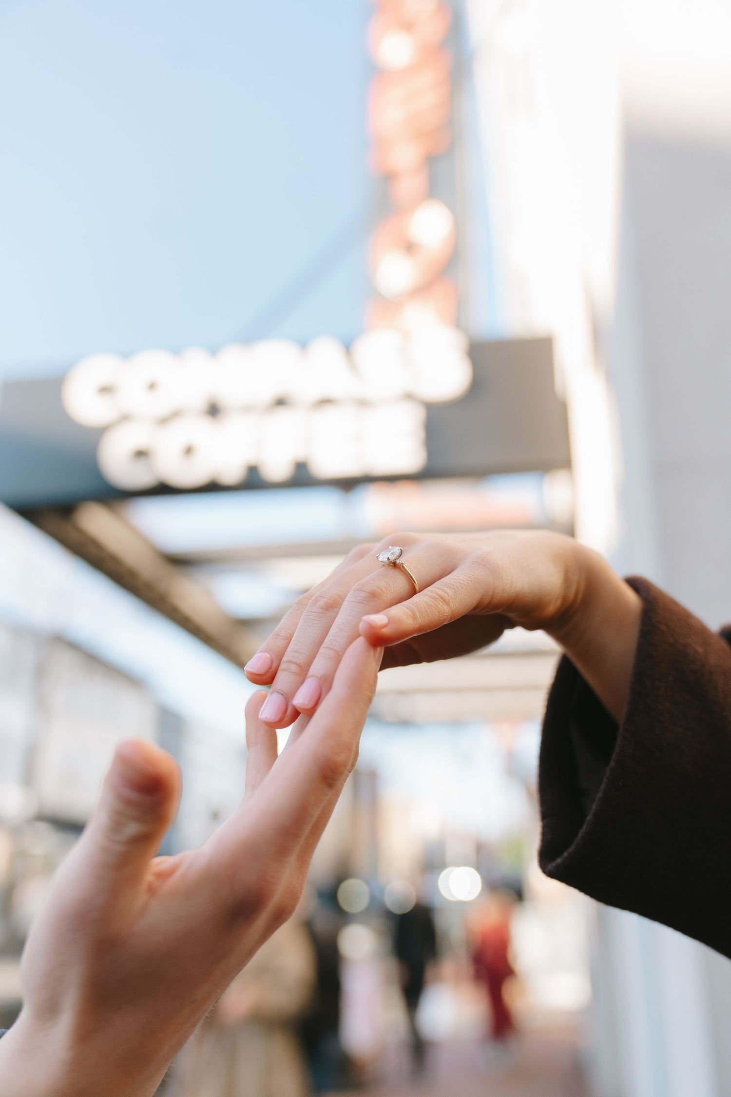 A person placing a diamond engagement ring on a partner's finger outside Compass Coffee shop in Georgetown in Washington, D.C.