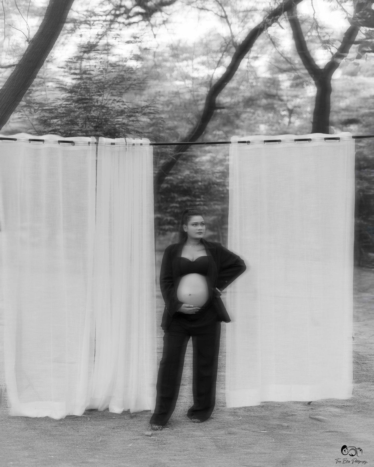 A series of black and white photographs showing a figure interacting with hanging white sheets outdoors.