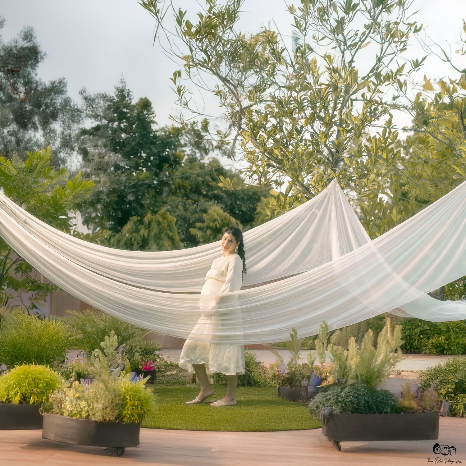 Flowing white fabric draped elegantly between poles creates an ethereal outdoor canopy setting in a garden space.
