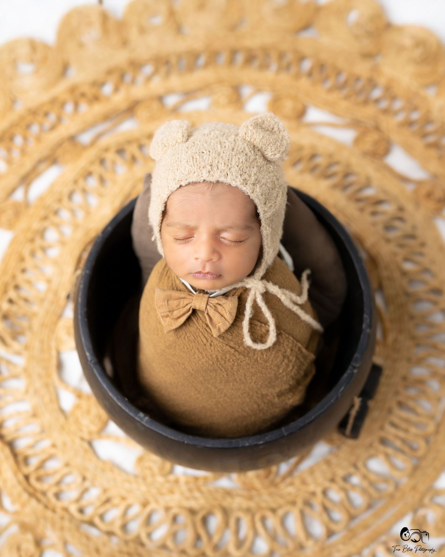 A series of sepia-toned newborn photography shots showing a sleeping baby in tan knit props and decorative backgrounds.