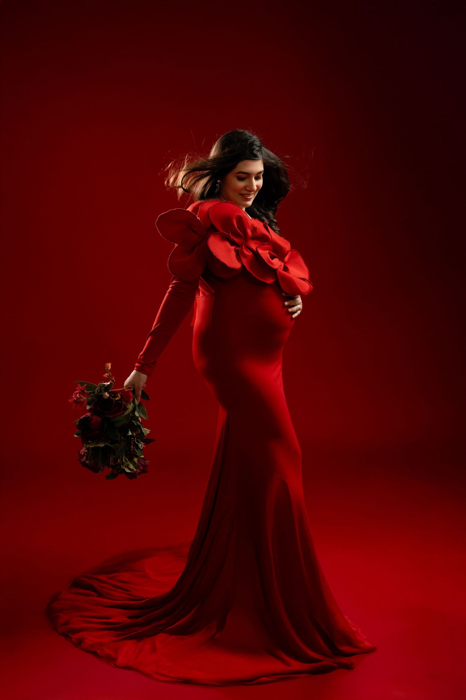 A dancer in a flowing red dress performs an elegant twirling motion against a deep red background.