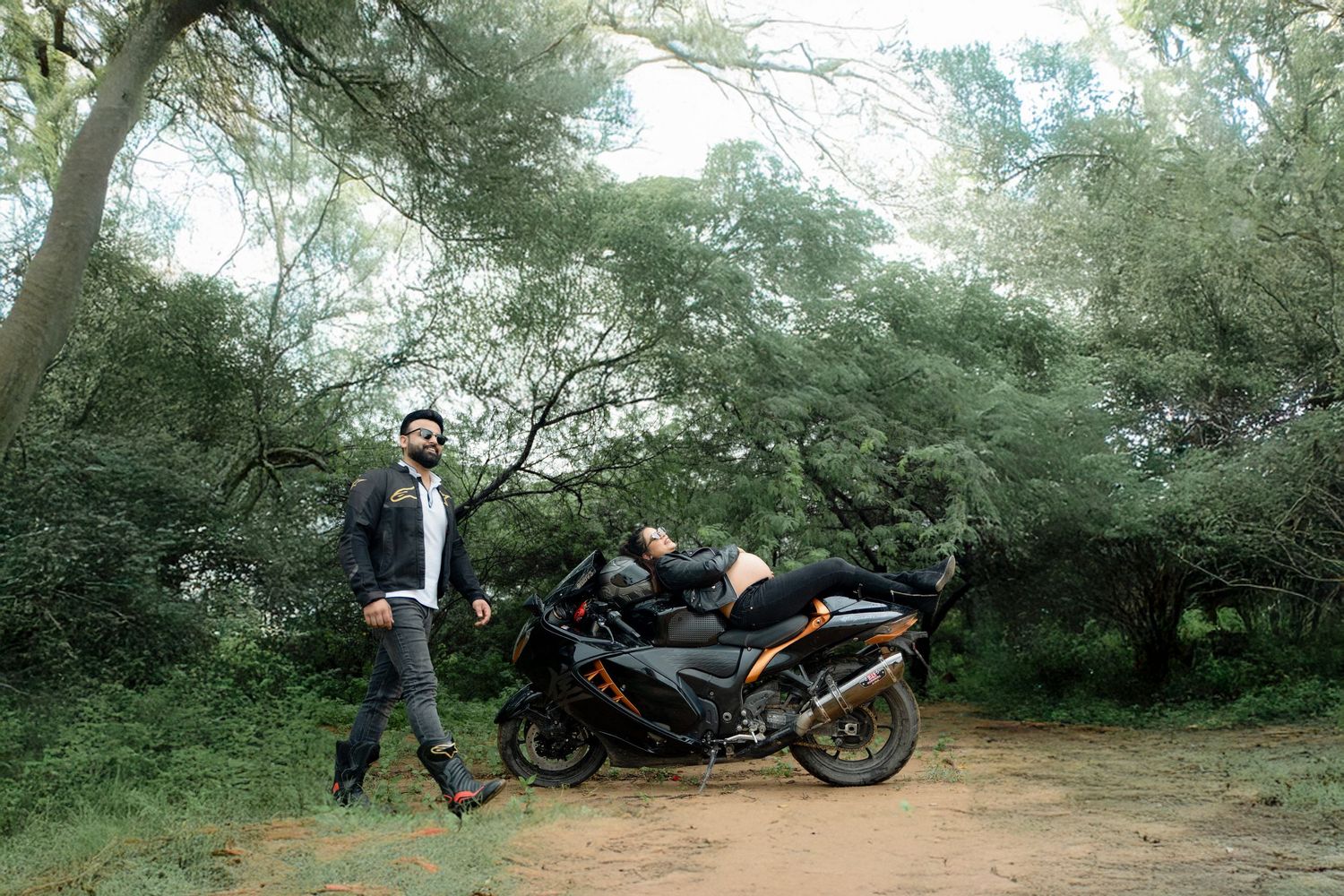 A video compilation showing someone performing motorcycle stunts and wheelies in a wooded outdoor area.