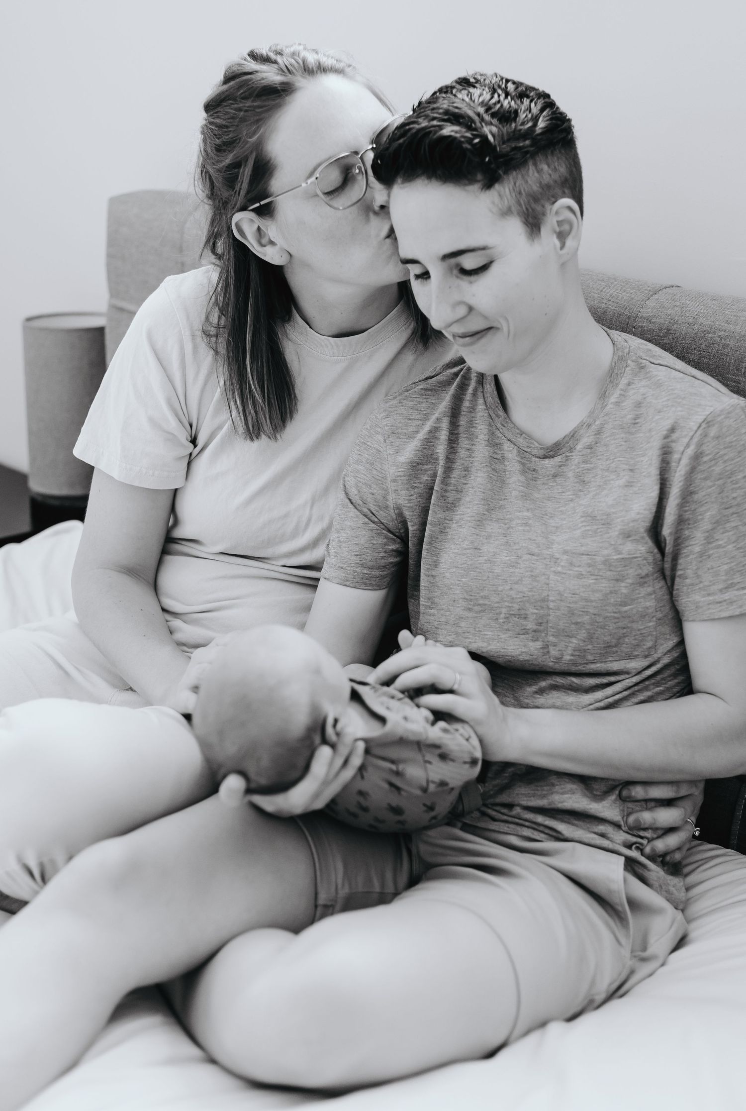 An intimate black and white portrait of a couple sharing a tender moment with their baby.