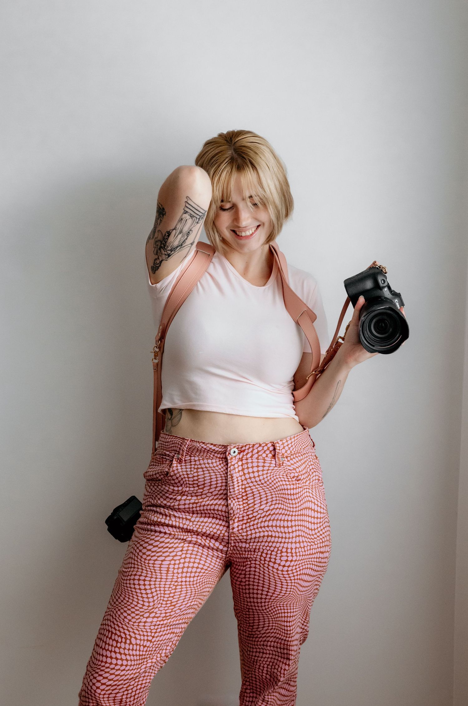 A photographer in pink patterned pants holds a professional camera against white background. Gippsland photographer. Melbourne photographer.
