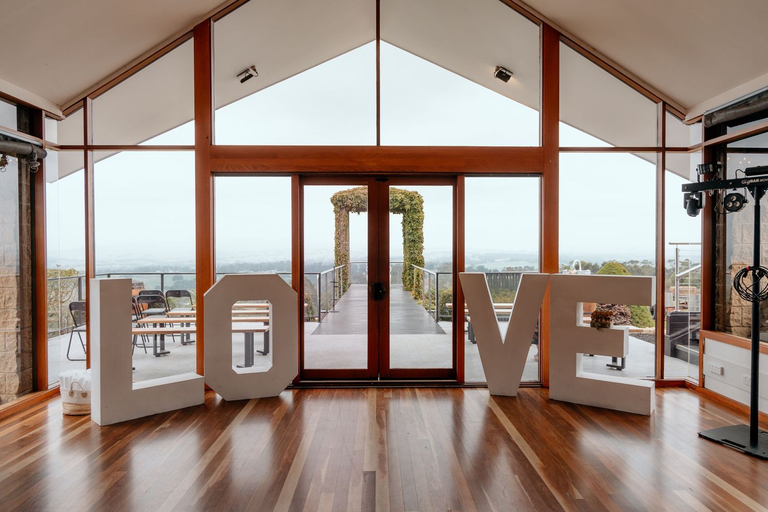 Panoramic view of an empty modern yoga studio with wooden floors and large windows overlooking a city skyline.