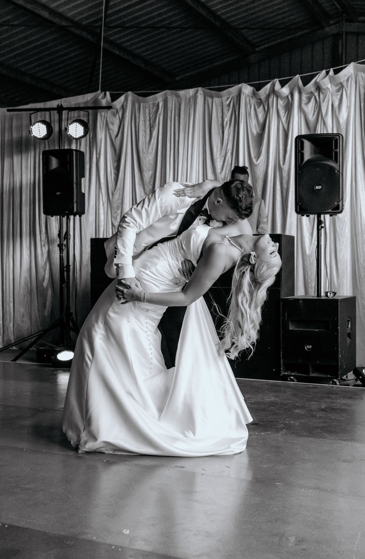 Bride and groom share a romantic dip kiss on the dance floor during their first wedding dance.