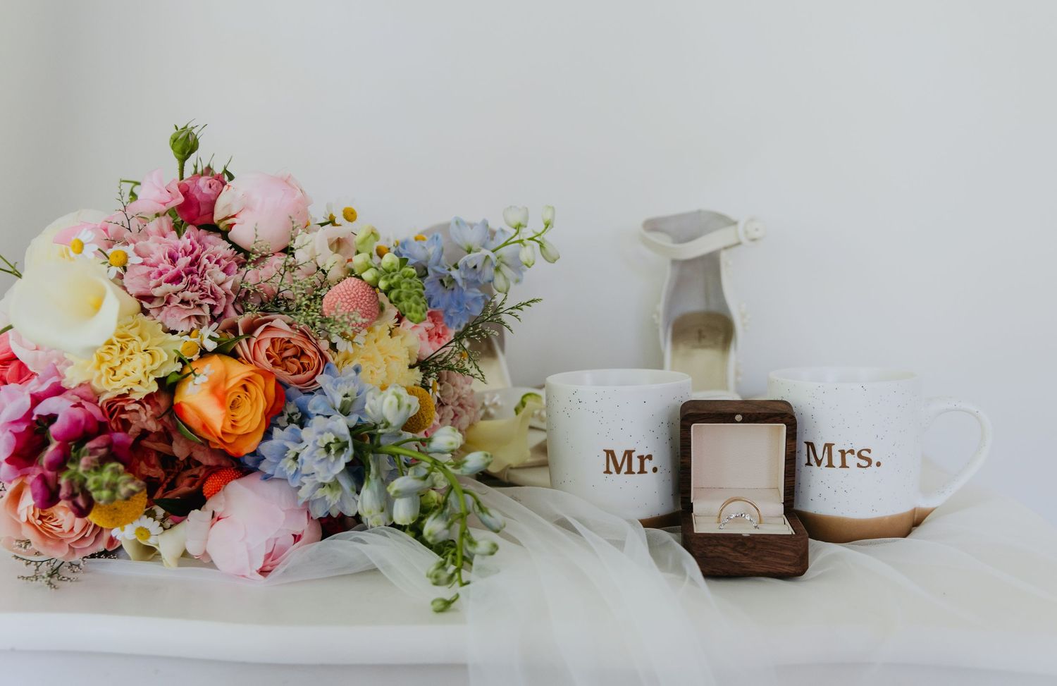 A romantic wedding photo collage featuring floral arrangements, rings in boxes, and Mr. and Mrs. signage.