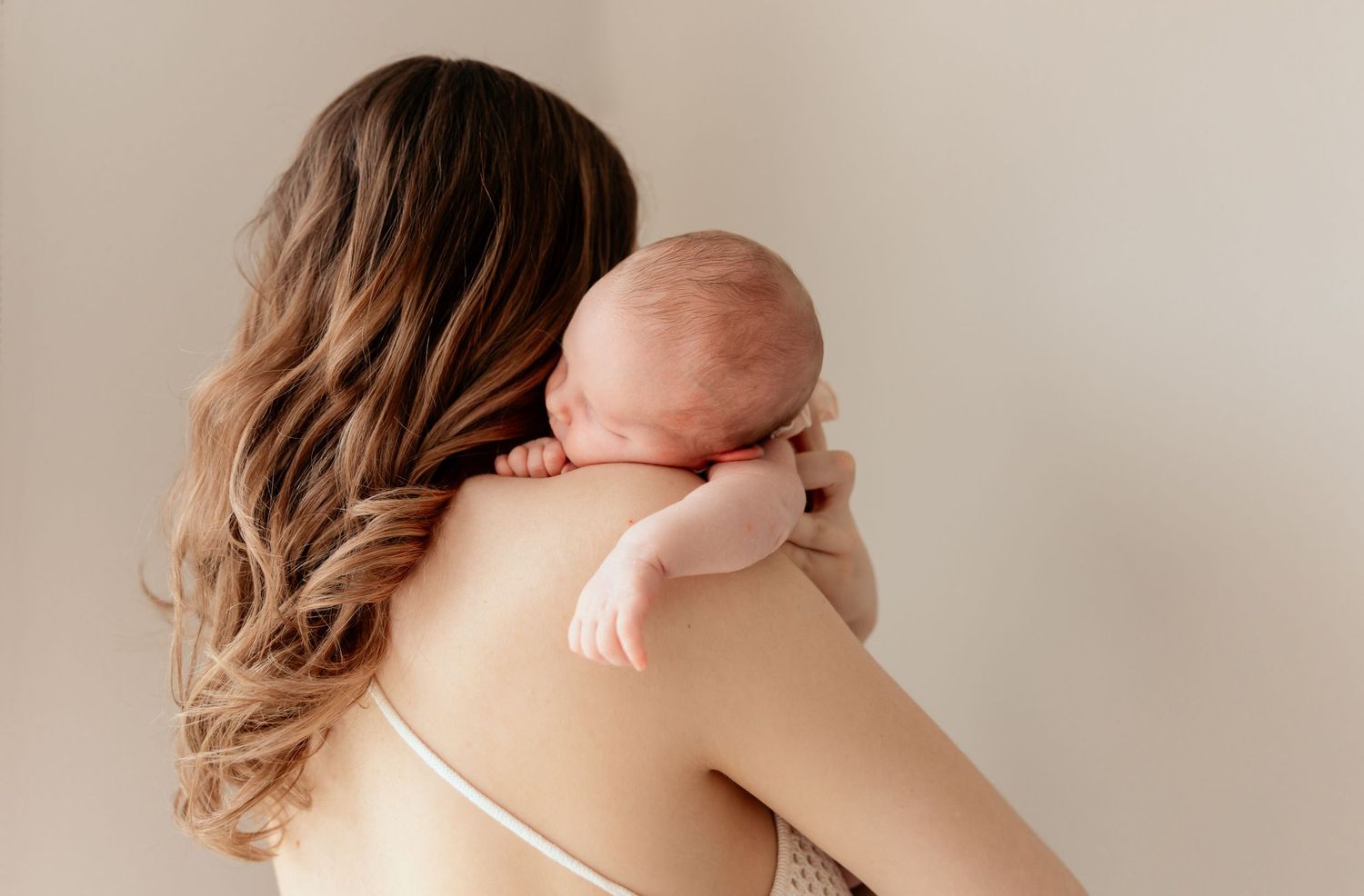 A gentle moment showing parent holding sleeping infant against shoulder.
