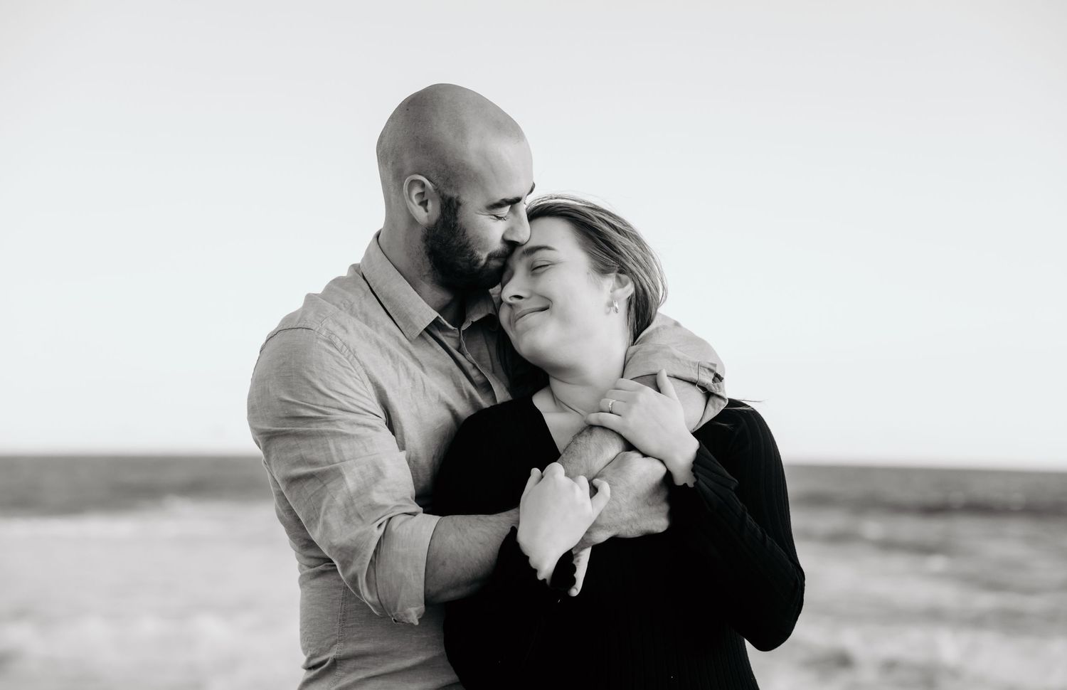 Tender black and white moment of couple embracing outdoors.