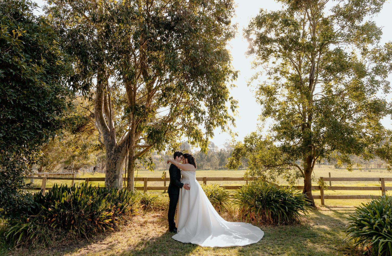 Romantic sunset wedding portraits taken in a lush outdoor setting with golden sunlight filtering through trees.