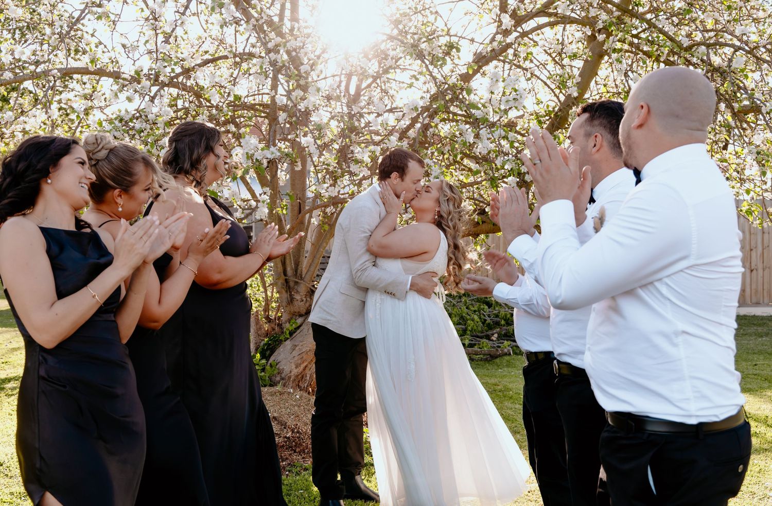 Couples dancing together outdoors under blooming cherry blossom trees in a romantic springtime setting.