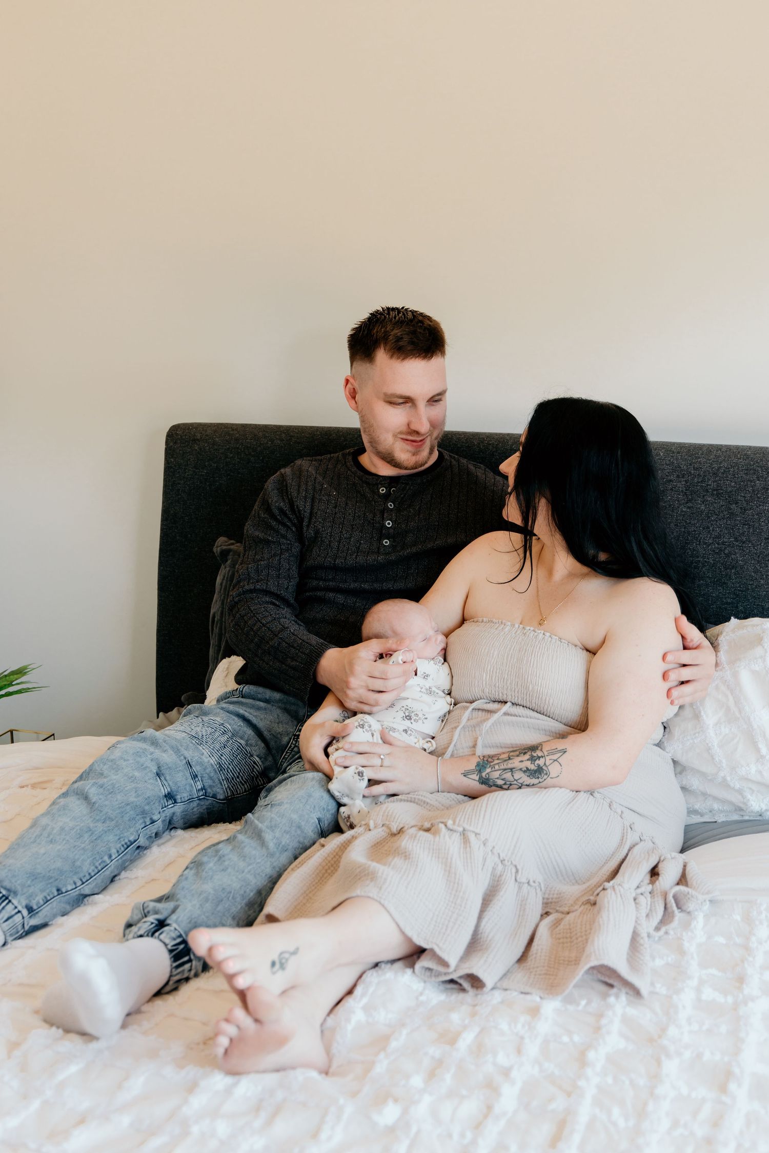 Couple sharing tender moment while relaxing on bed with light neutral tones.