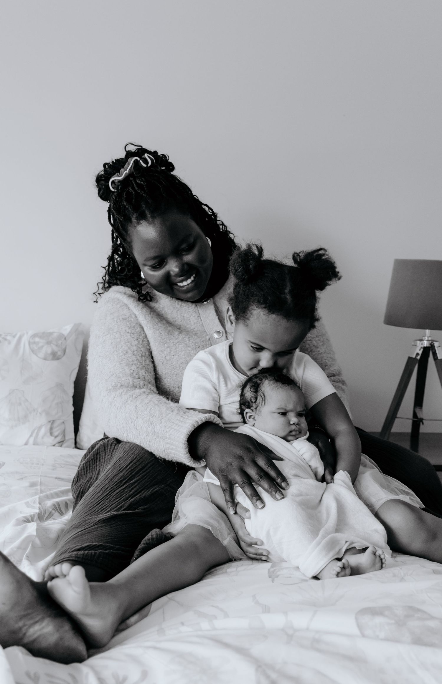 Black and white photo sequence showing tender moments of cuddling and bonding on white bedding.