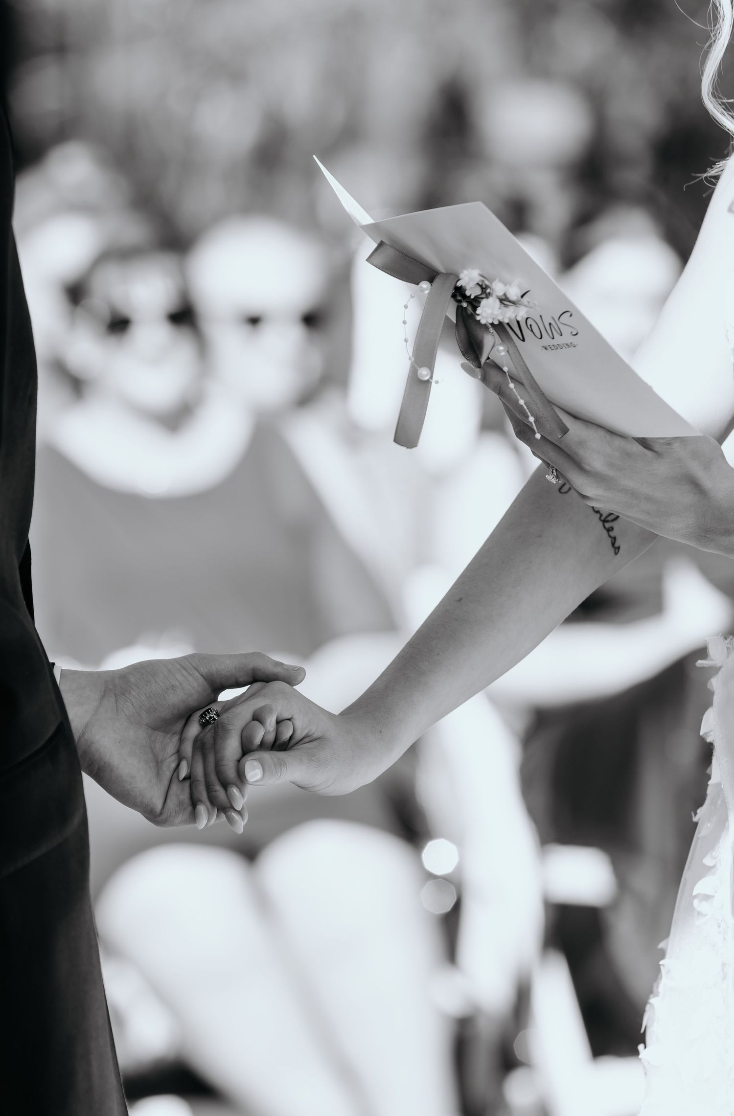 Hands holding ripped or torn pieces of paper in a black and white artistic composition.