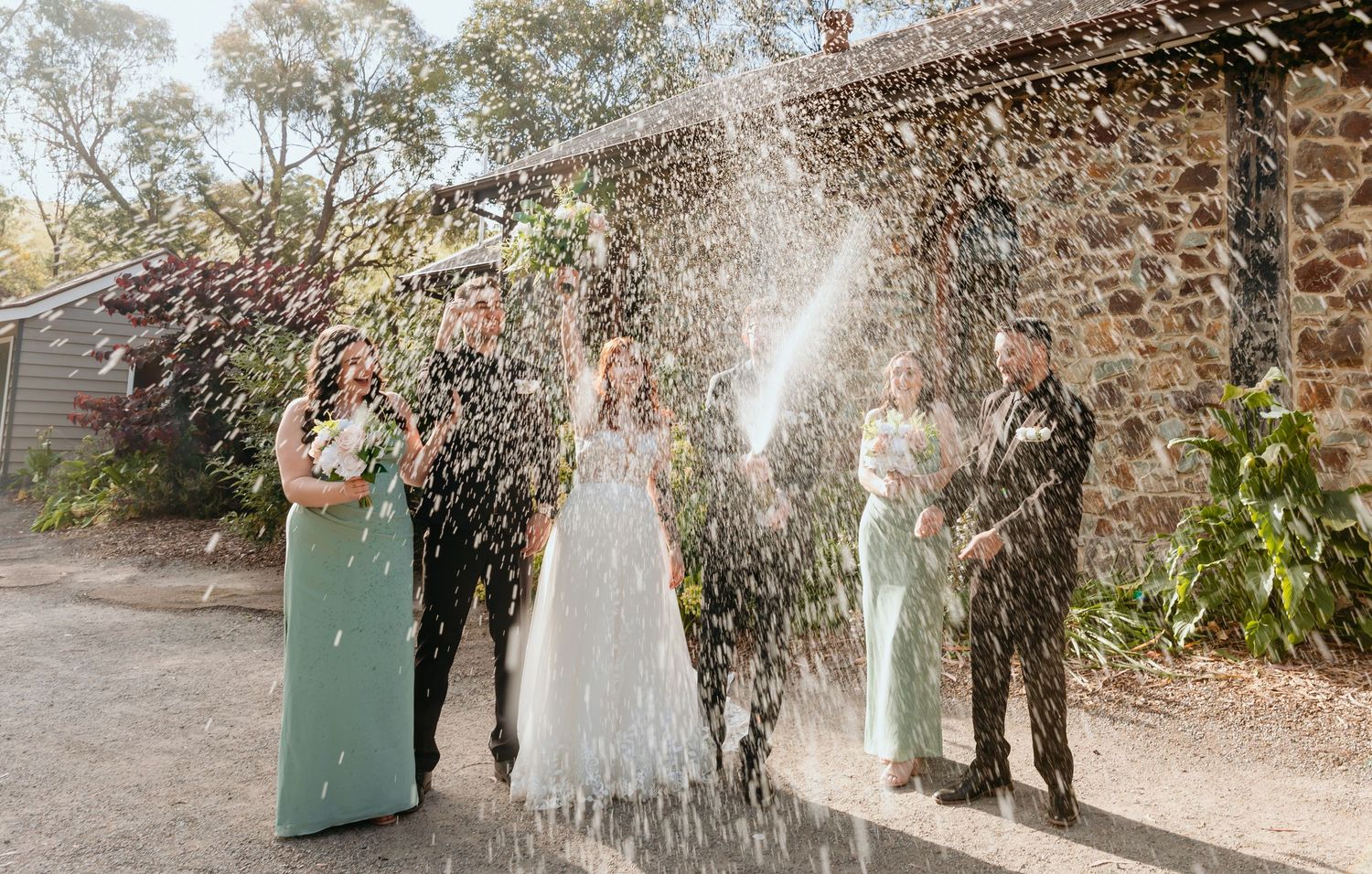 Scenic garden wedding venue path lined with decorative wisteria vines and planters in natural outdoor setting.