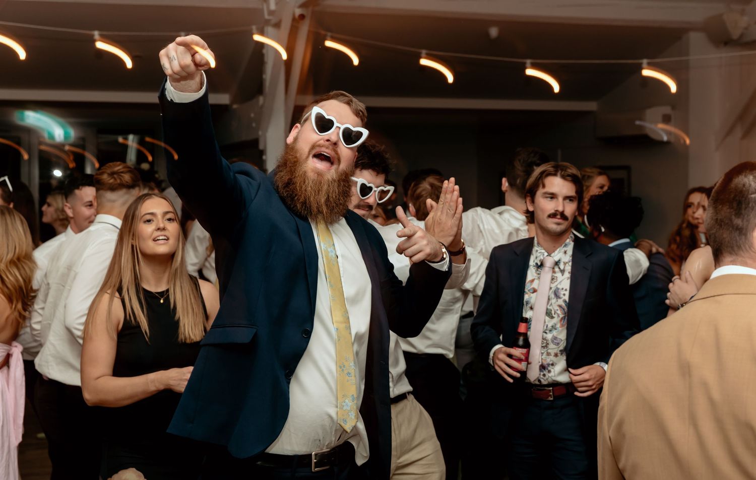 Wedding guests dancing and celebrating on the dance floor at a reception party.