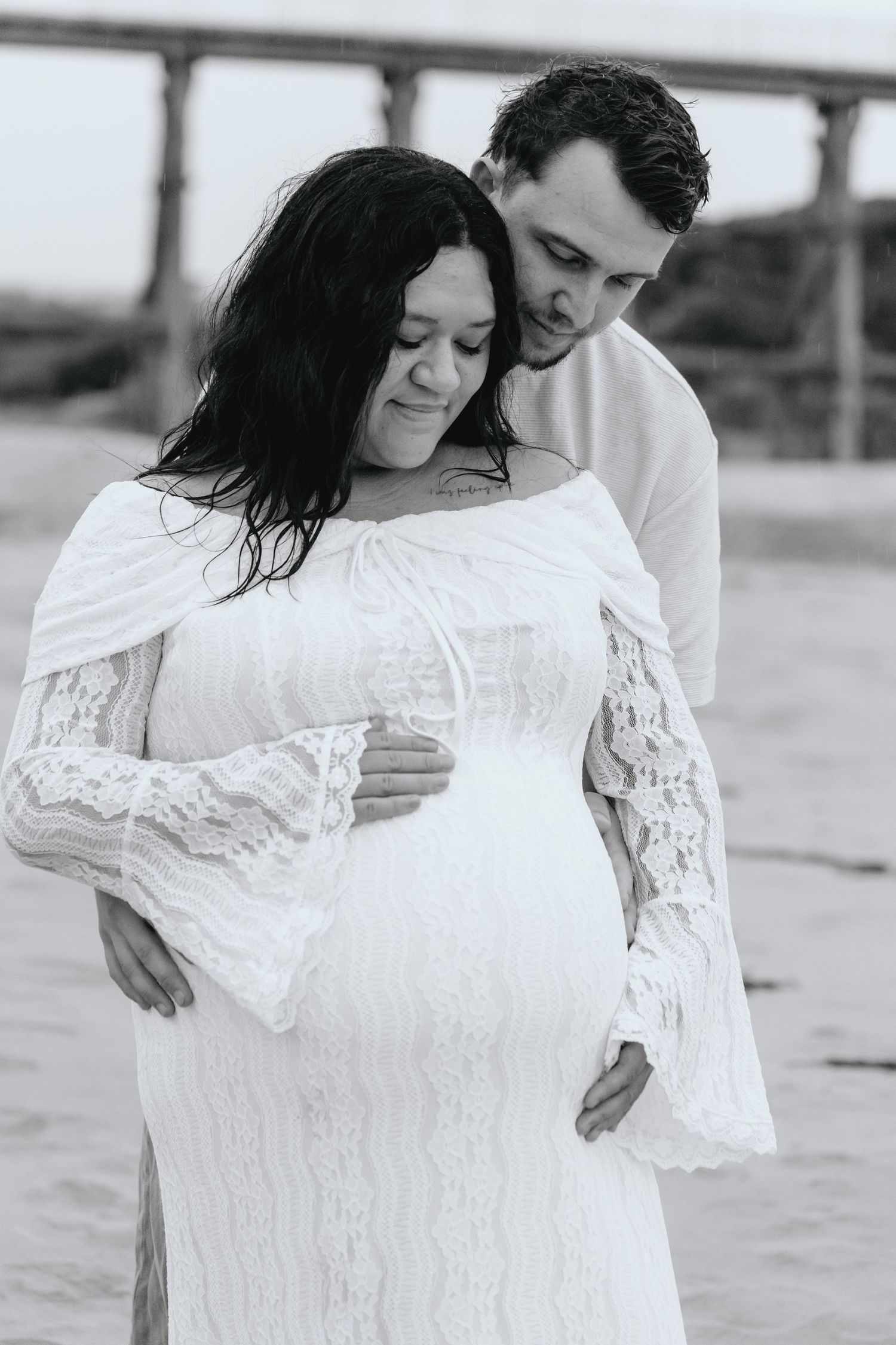 A romantic black and white series of photos showing a couple embracing on a beach in white clothing.