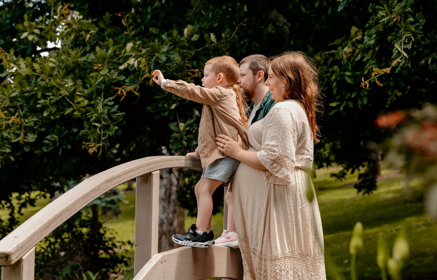 Family enjoying time together on wooden bridge in garden setting.