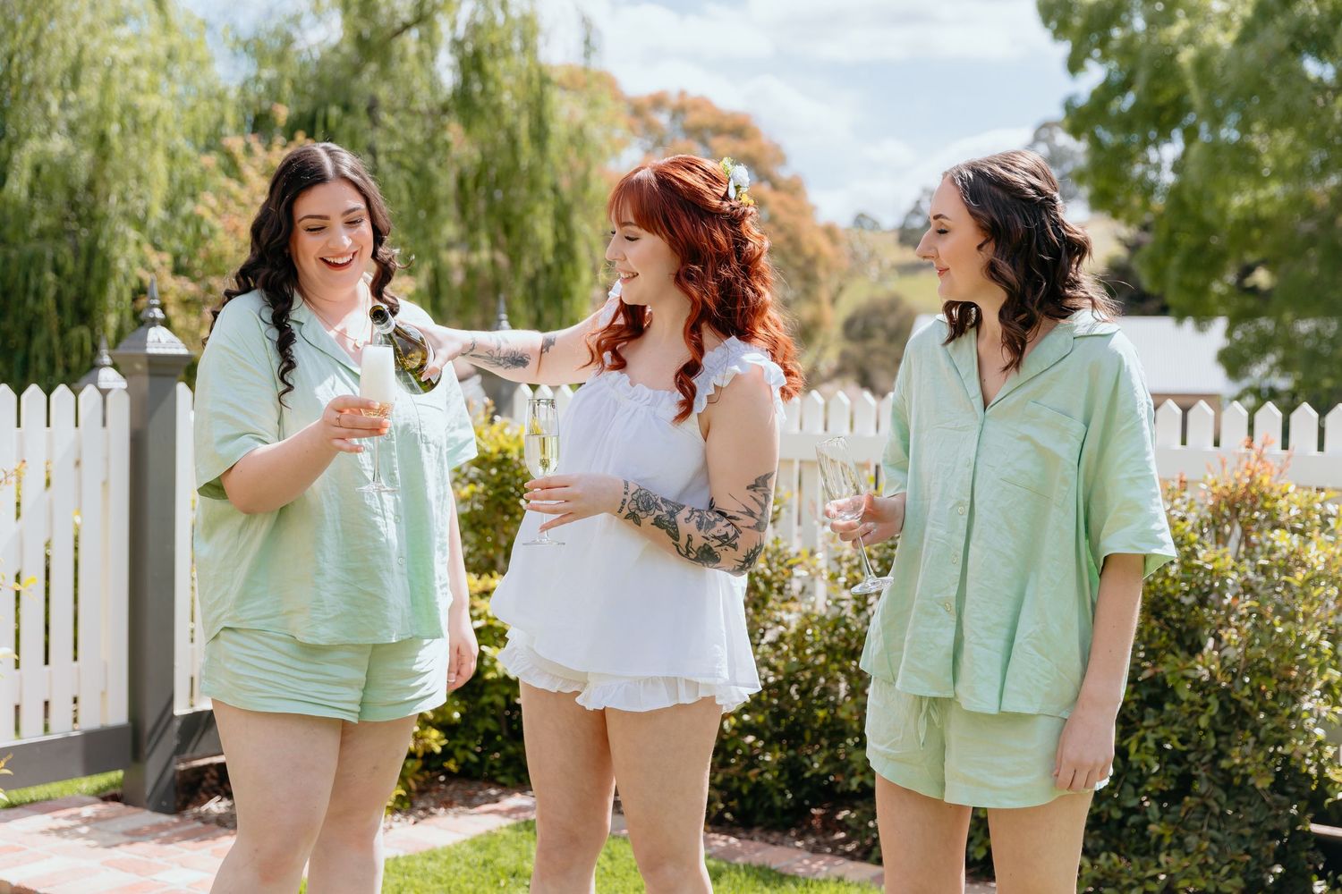 Group of friends in mint green and white outfits laughing and enjoying a sunny summer day outdoors.