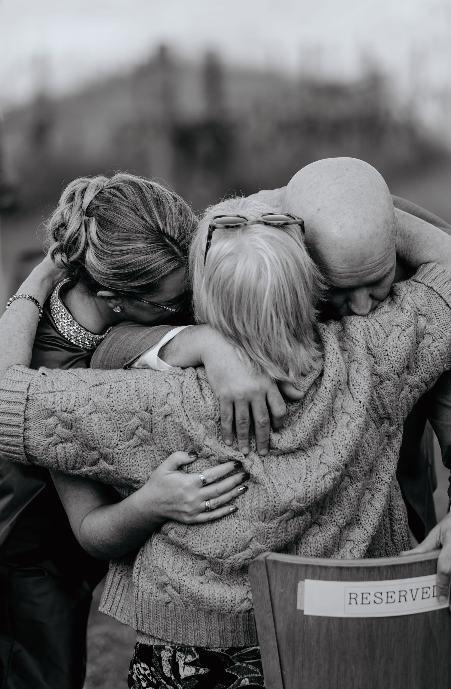 A black and white photo series showing people in sweaters hugging in a line formation.