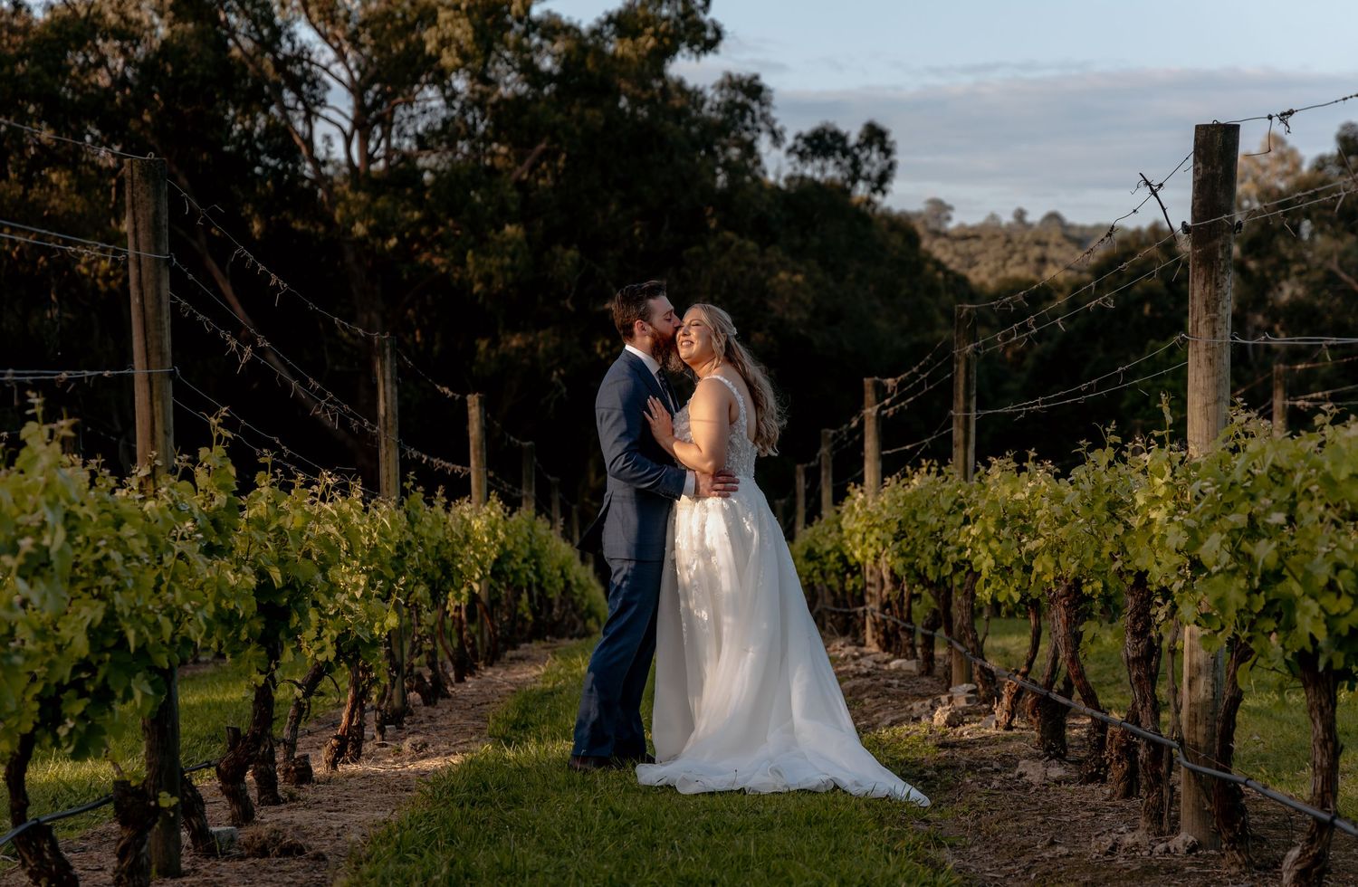 Scenic vineyard rows stretch into the distance under cloudy skies at a winery wedding venue.
