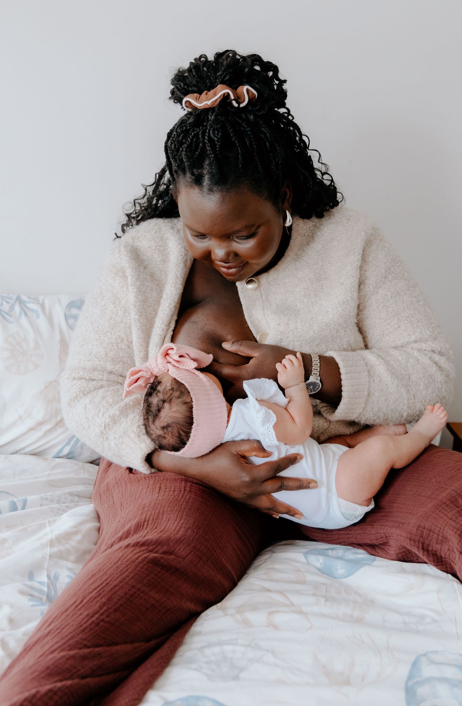 A tender moment of parent and newborn baby bonding while lying on white bedding.