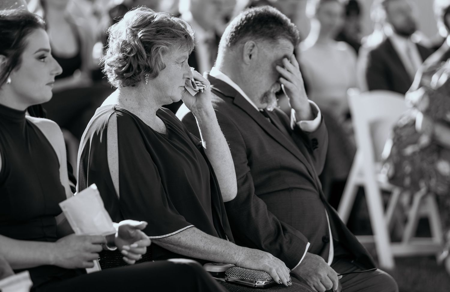 Black and white photo of people in formal attire at an event, with some holding drinks and engaged in conversation.