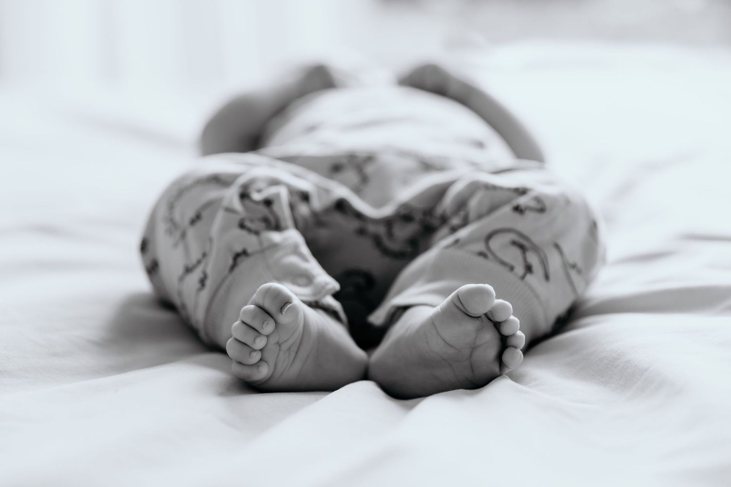 Black and white image of small baby feet in cozy wrapping.