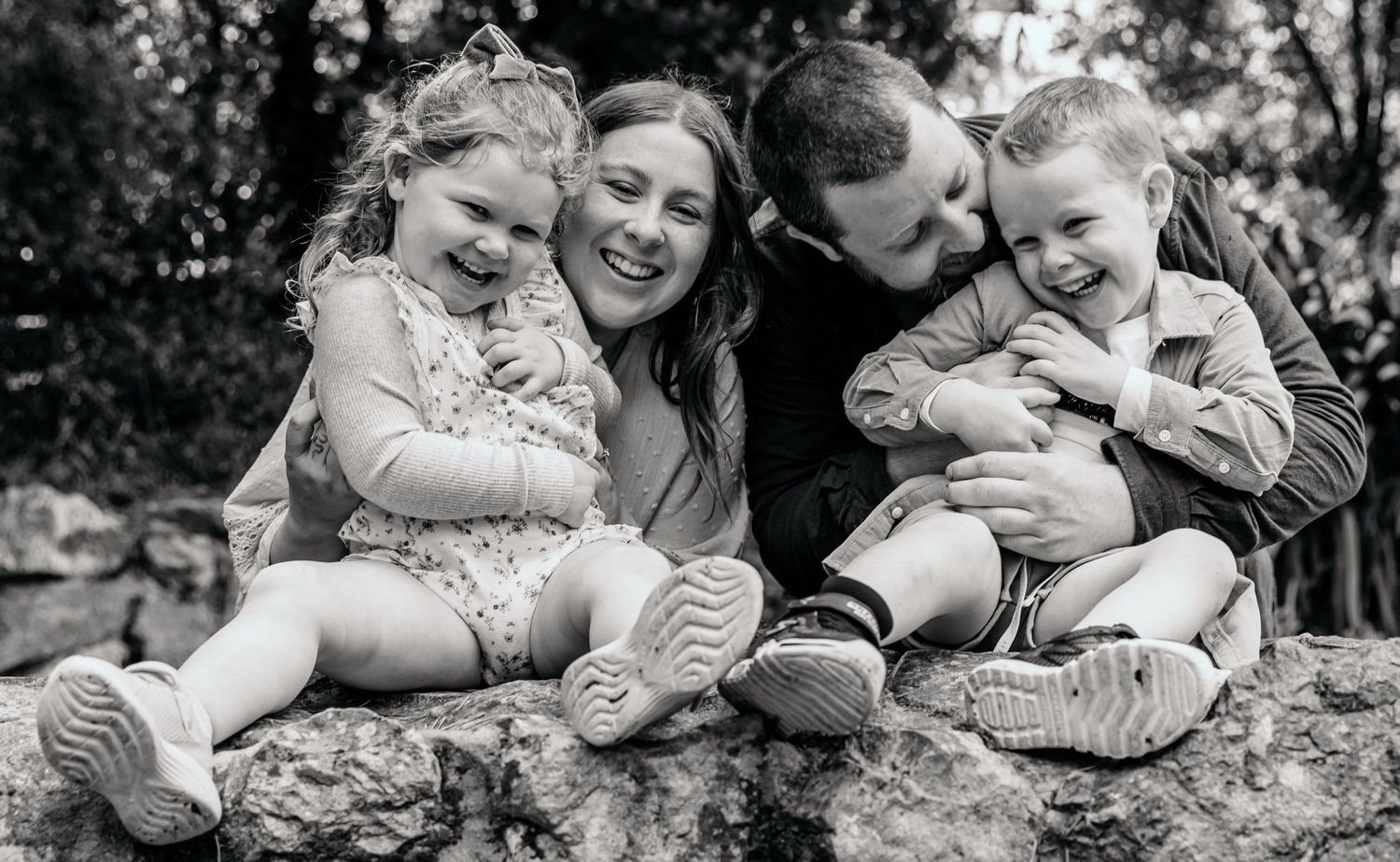 Black and white portrait of family sitting together outdoors.