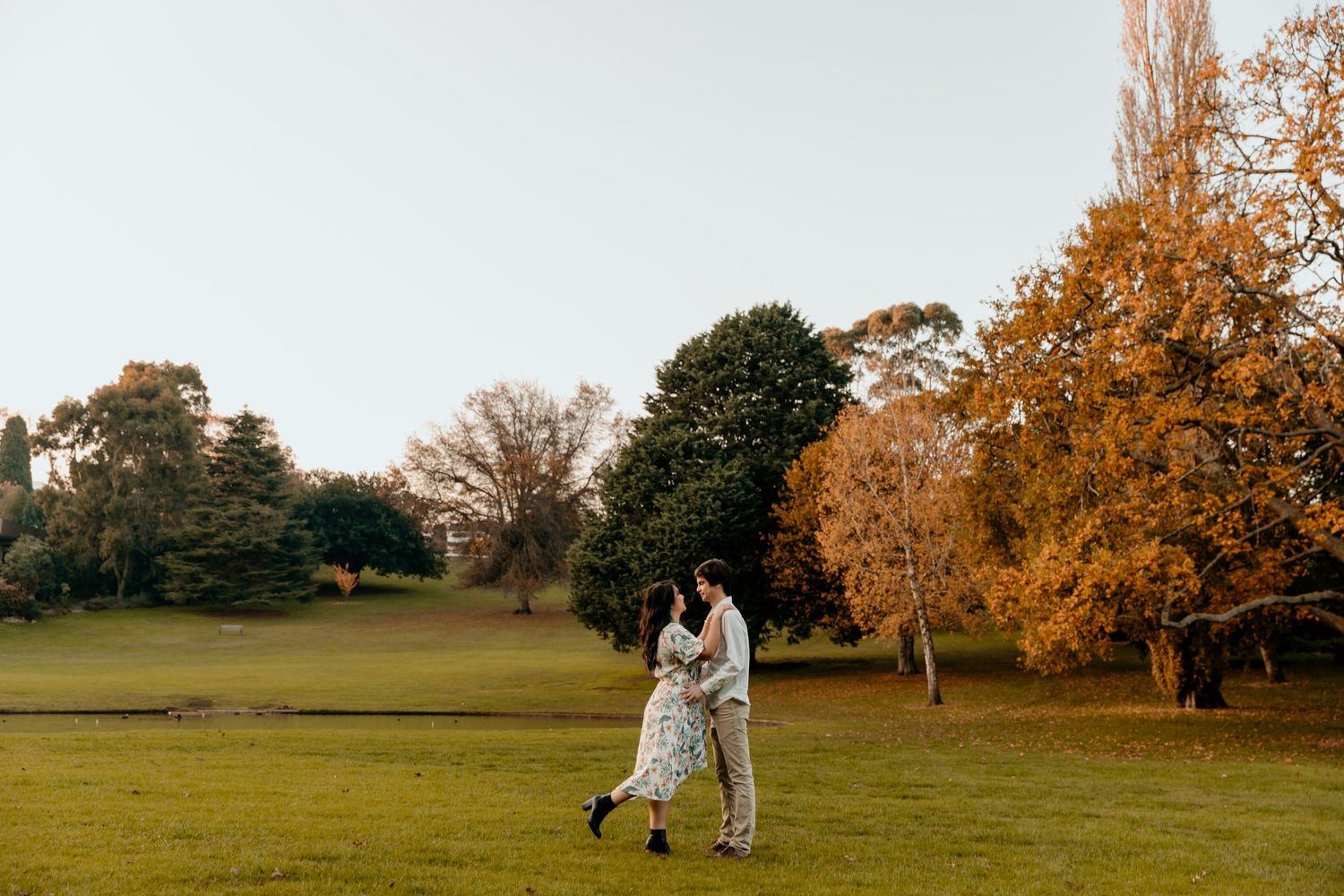 A couple walks together in a park with golden autumn trees in the background. Gippsland photographer. Melbourne photographer.