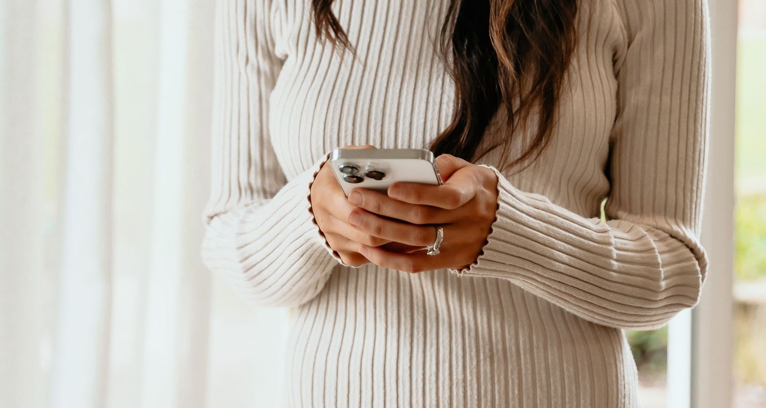 Close up of hands holding white coffee mug wearing cream ribbed sweater.