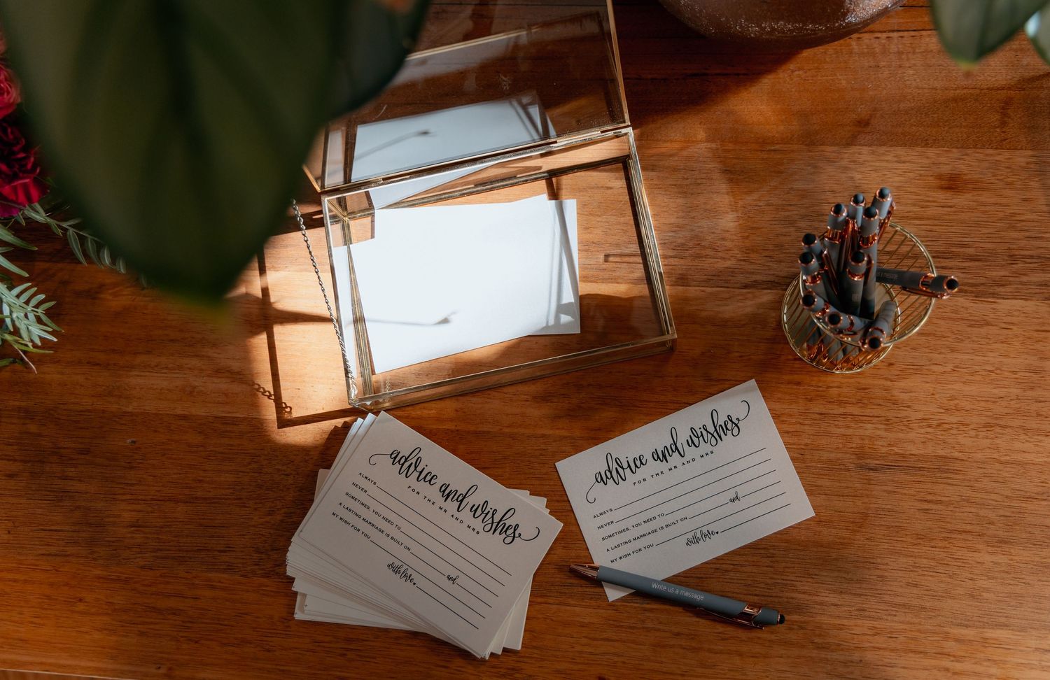 White recipe cards with handwritten notes laid out on a rustic wooden table with greenery accents.