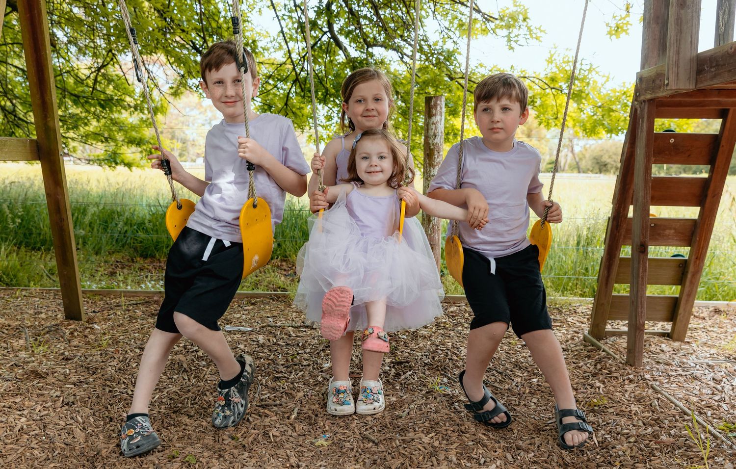 Children playing together on swings at a backyard playground set.