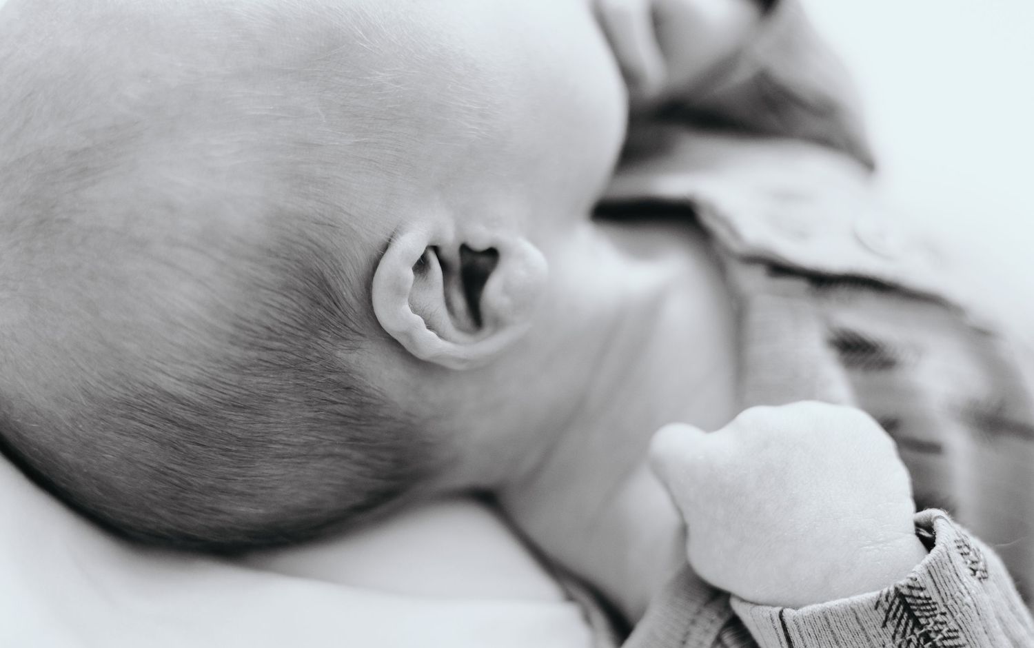 Close-up black and white portrait of a sleeping baby's ear and head.