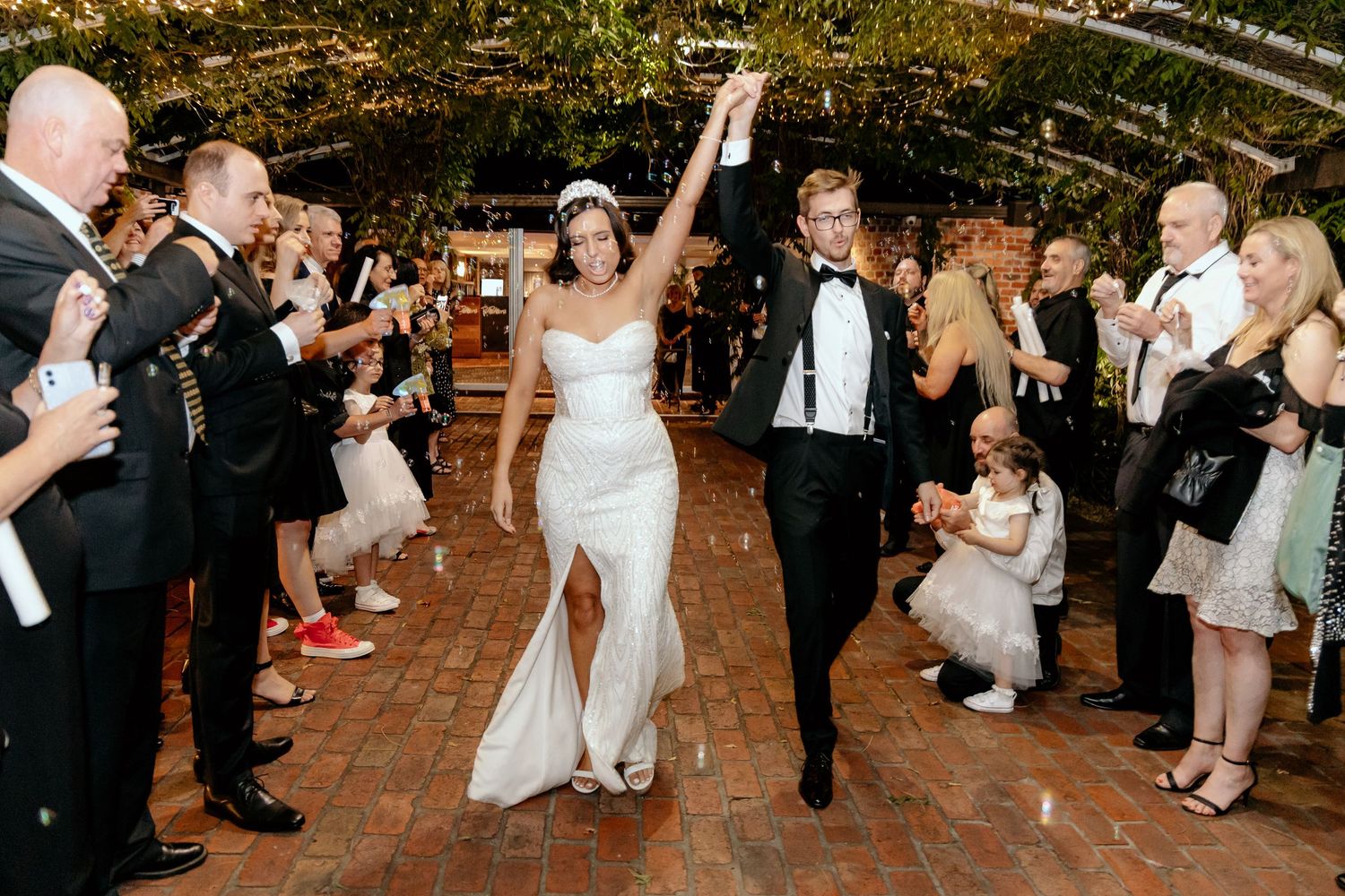 Wedding guests dance and celebrate together on a rustic wooden dance floor during the reception party.
