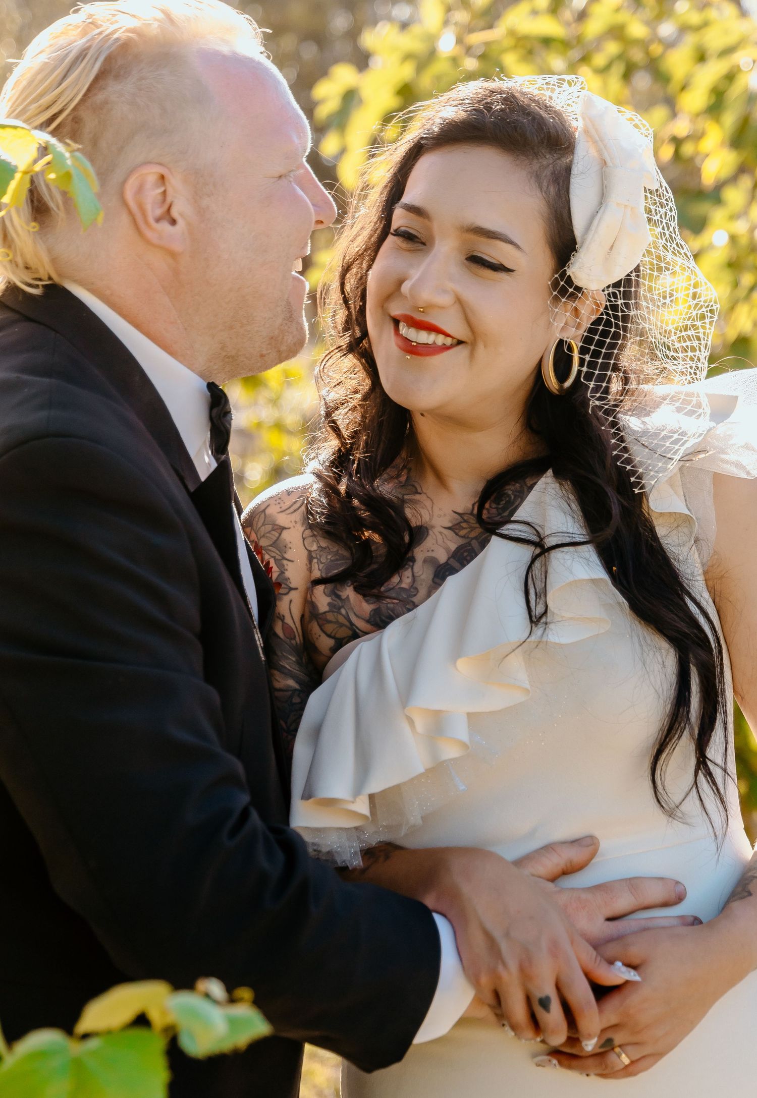 A couple in elegant wedding attire share intimate embraces outdoors in warm autumn sunlight.