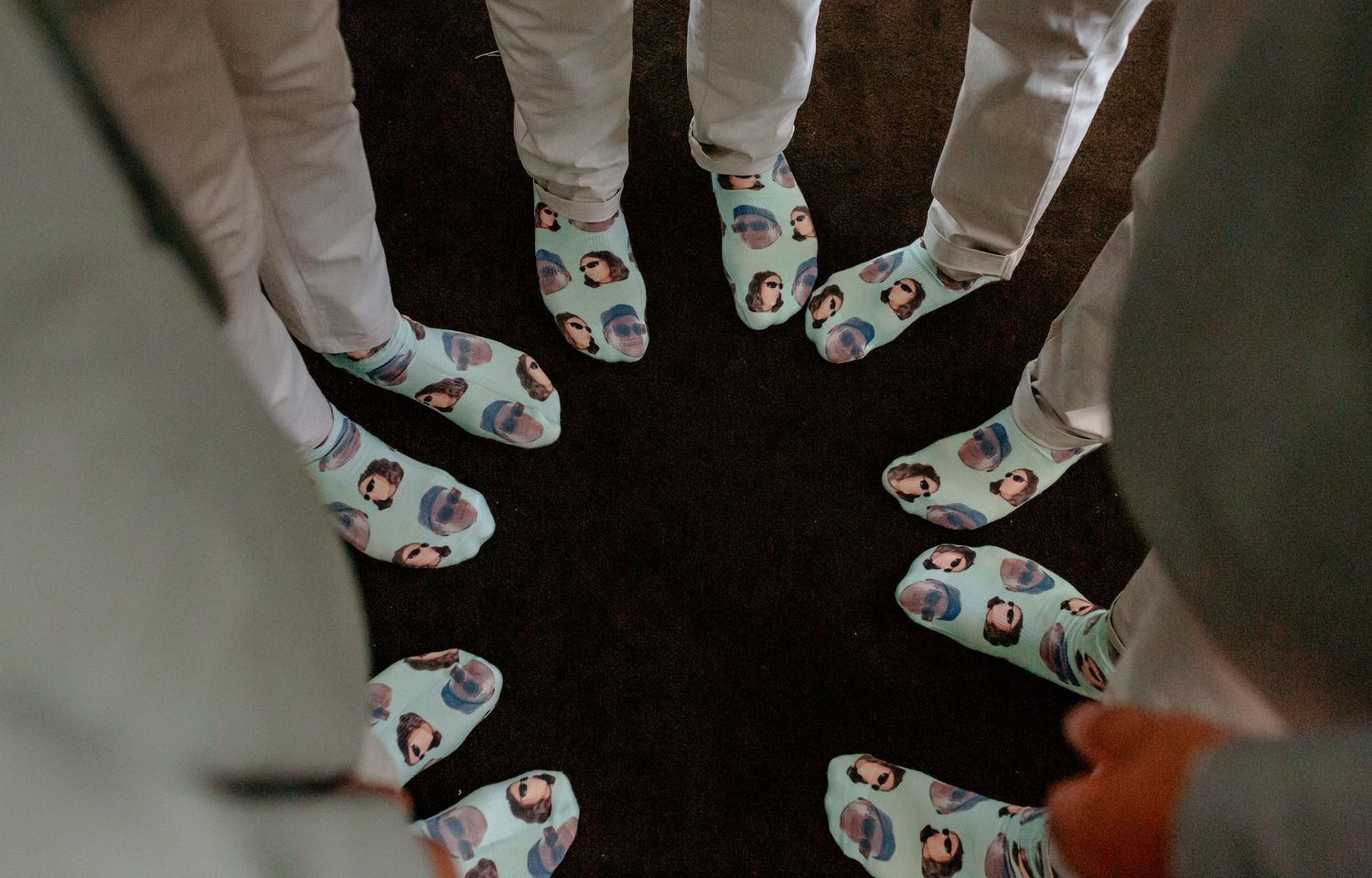 Multiple pairs of white socks with colorful coffee cup patterns arranged in a circular formation on a dark surface.