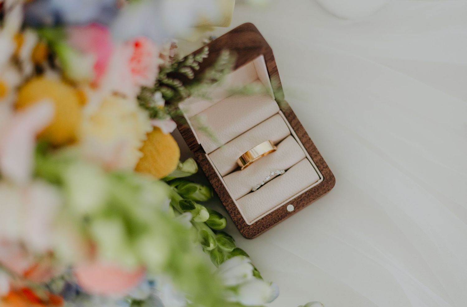 A rustic wedding setup features white floral arrangements with greenery and brown wooden accents in a natural setting.