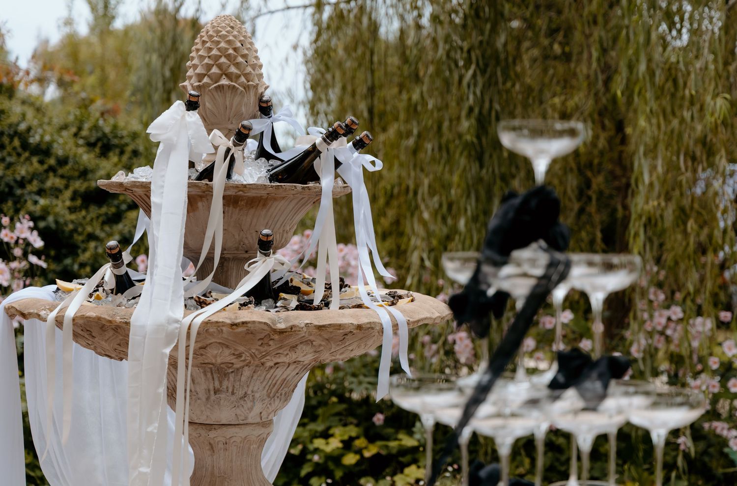 Elegant stone garden fountain decorated with white ribbons and black birds at wedding venue.