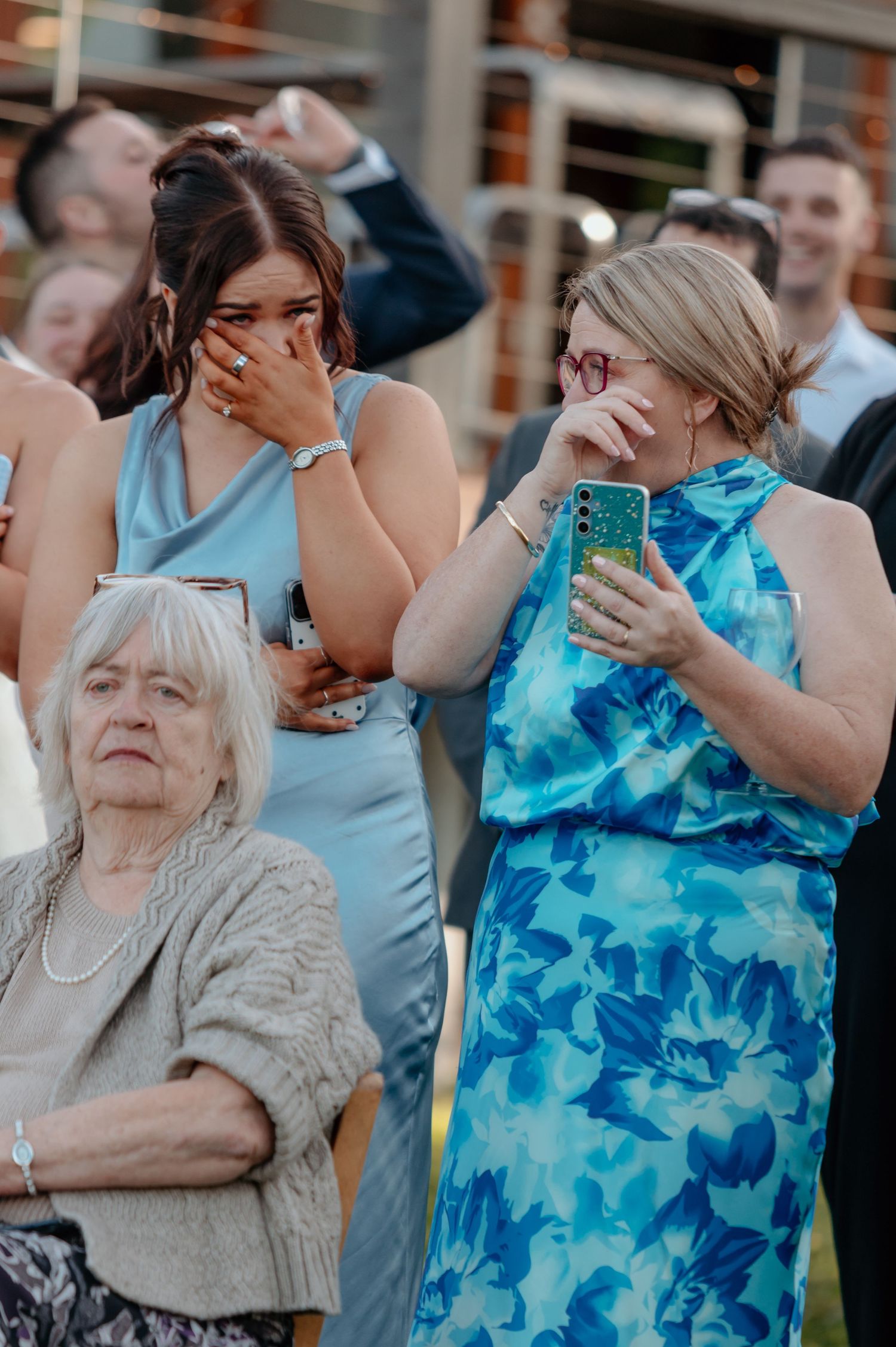 A sequence of emotional reactions showing people in blue dresses and formal attire at what appears to be an outdoor event.