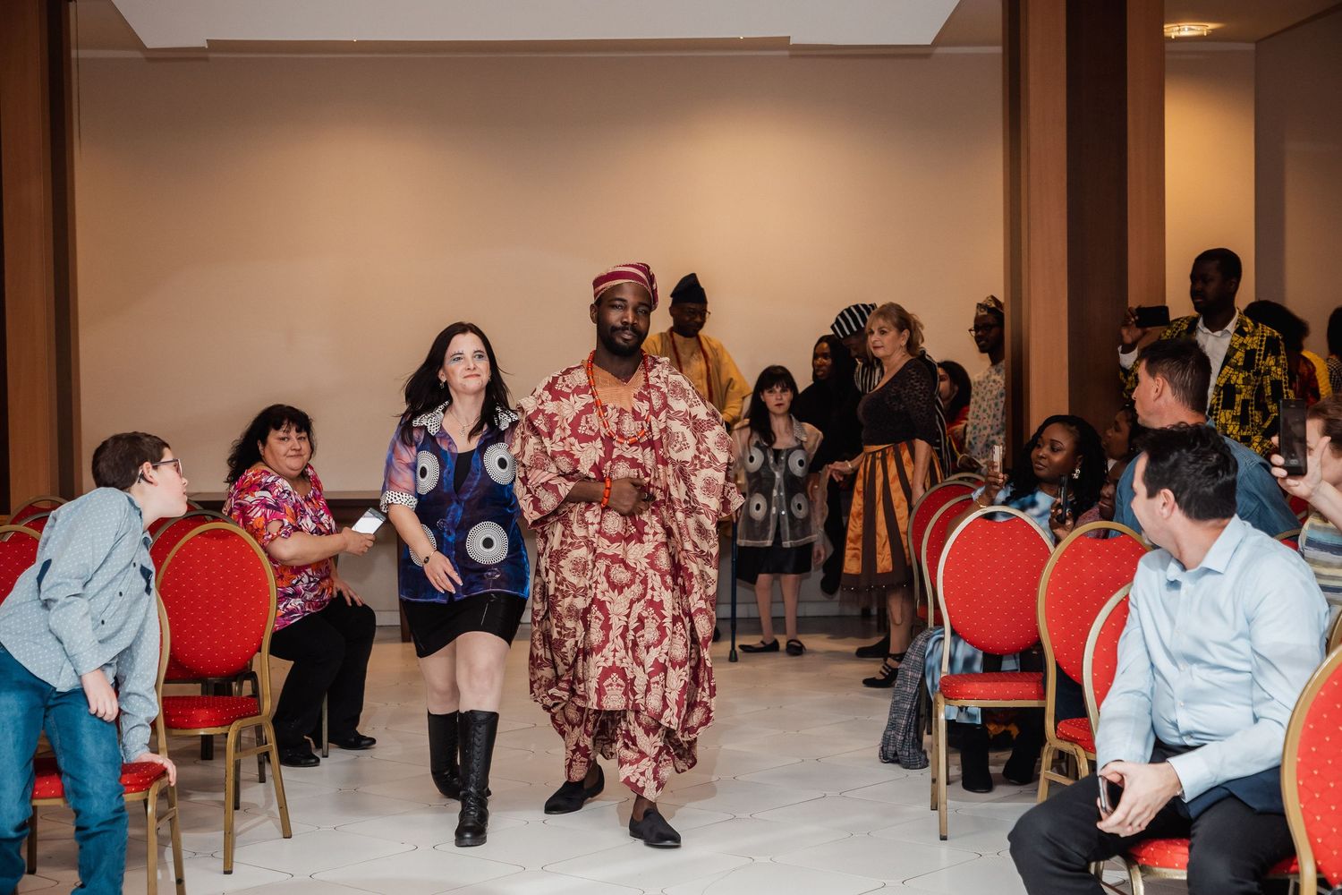 Diverse models walk the runway in colorful African traditional attire at a multicultural fashion show.