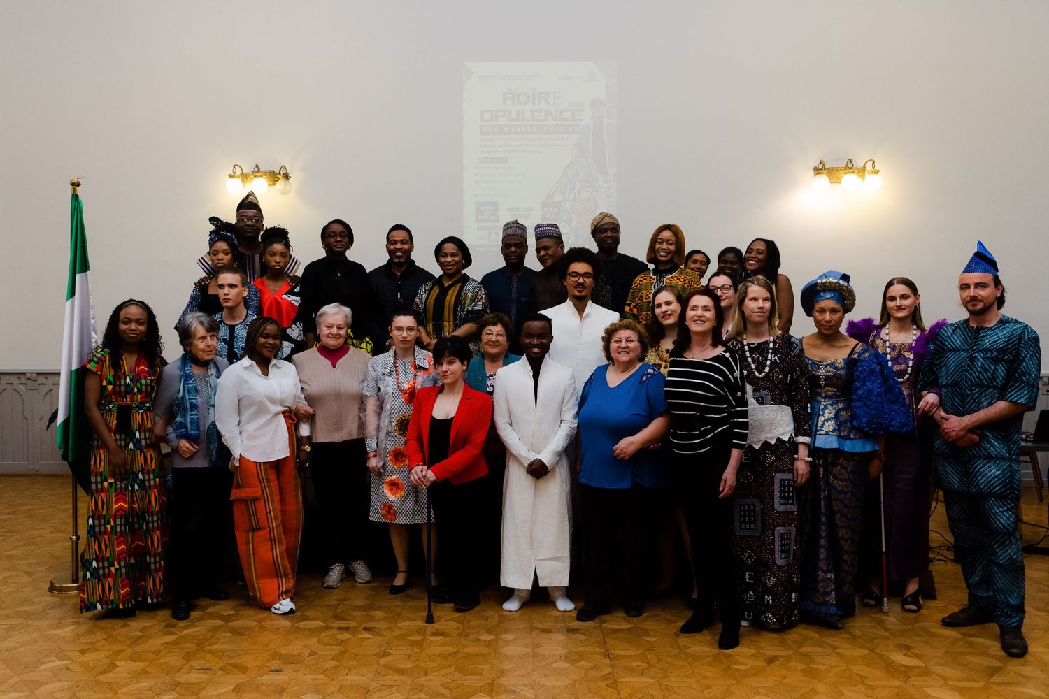 Large diverse group photo at a formal Nigerian cultural event, with attendees in traditional and Western attire posing together.