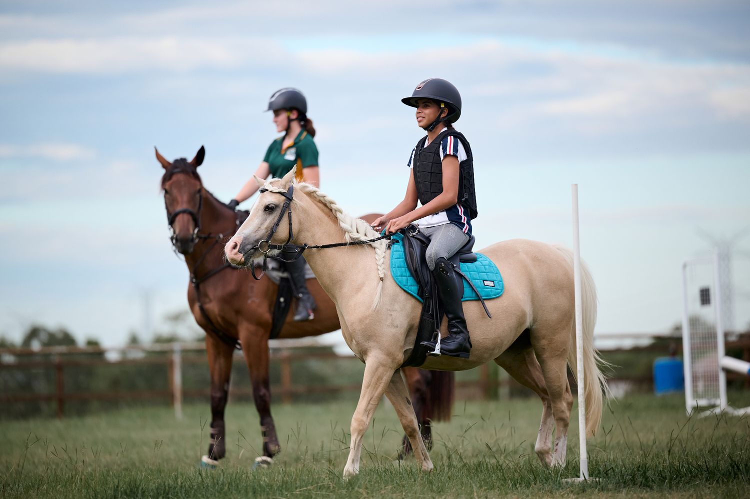 Two horses and their riders practicing in a training field under blue skies in Brisbane Queensland.