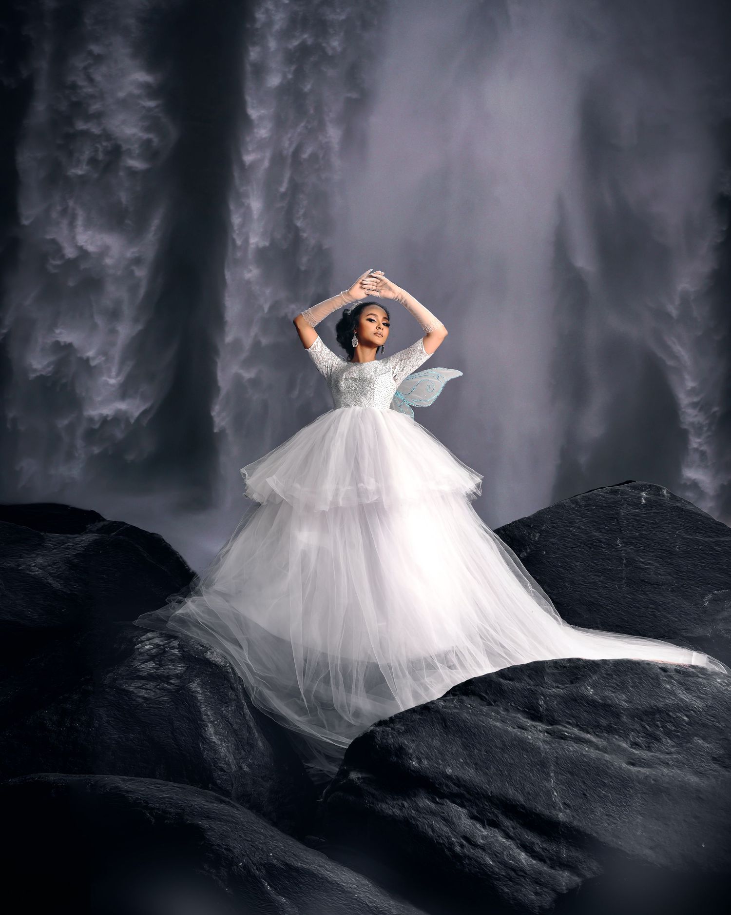 The Fairy Bride' — a lady in a white dress and wings, posing gracefully in front of a waterfall.