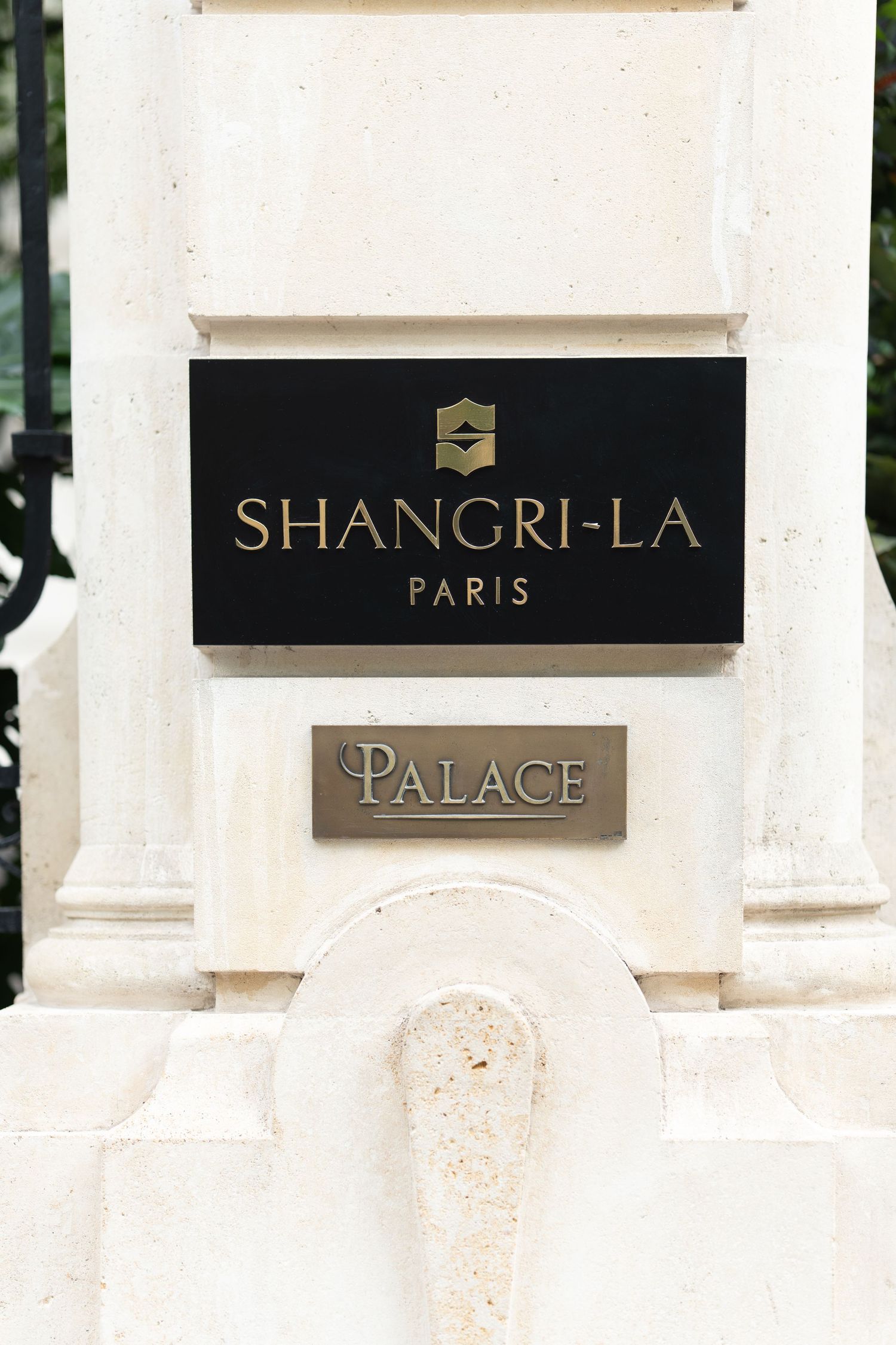 Close-up view of the elegant Shangri-La Paris hotel signage and Palace plaque mounted on a white stone exterior wall.